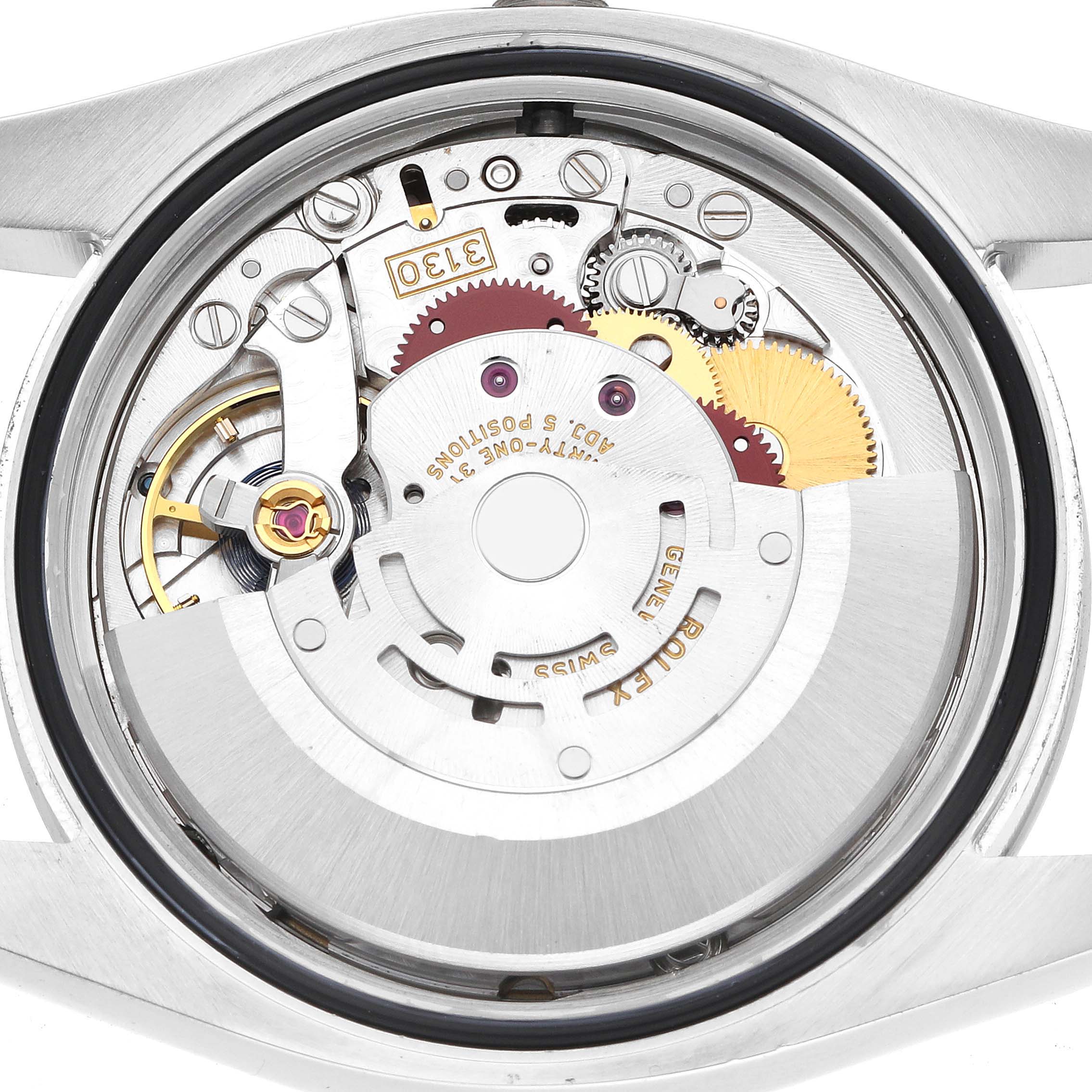 The image shows the movement of a Rolex Oyster Perpetual 116000 Men
s Stainless Steel Black Dial watch from a back angle, revealing gears and internal components.