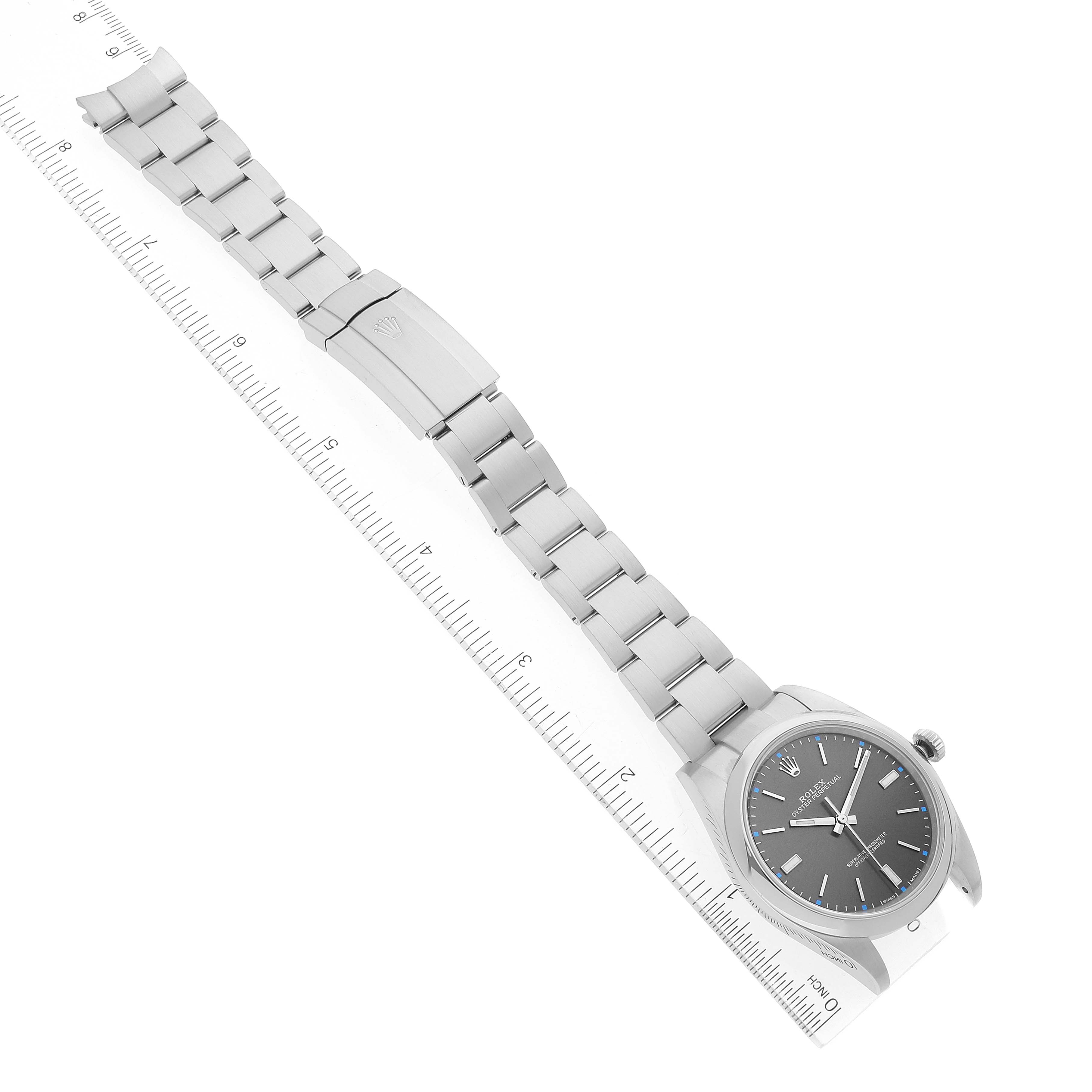 The image shows a full view of a Rolex Oyster Perpetual 114300 Men's Stainless Steel Grey Dial 114300 Men's Stainless Steel Grey Dial watch placed next to a ruler for scale.
