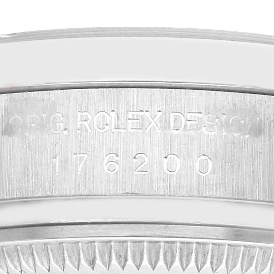 The image shows the edge of a Rolex Oyster Perpetual 176200 Women
s Stainless Steel White Dial model, focusing on the engraved bezel and serial number.
