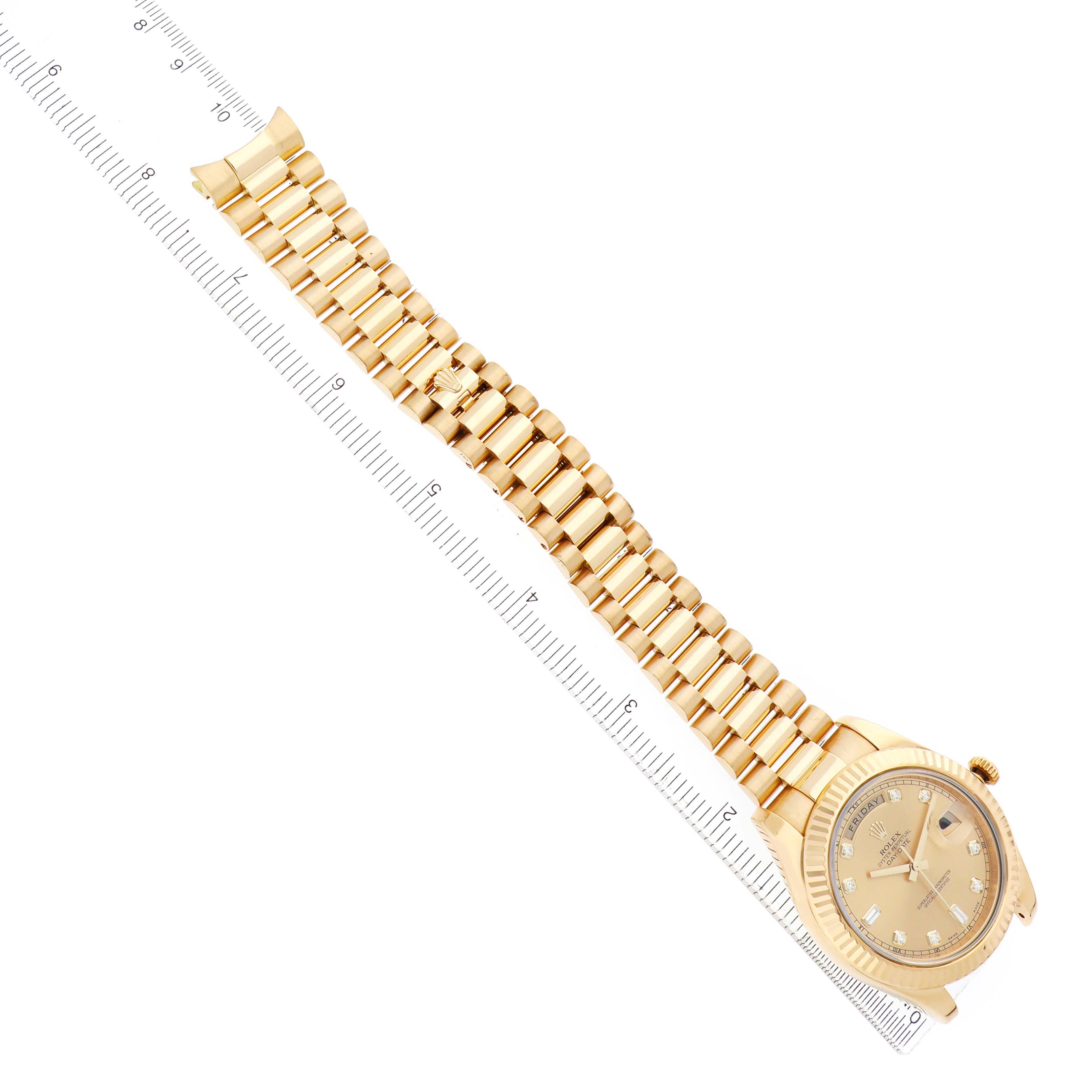 The Rolex President 218238 Men
s Yellow Gold Champagne Dial watch is shown from a top-down angle, highlighting the dial, bezel, and full bracelet with a ruler beside it.