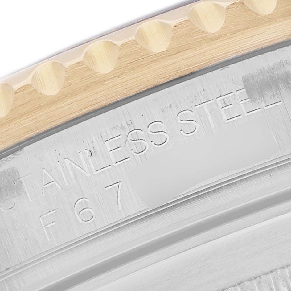 The image shows a close-up of the Rolex Submariner 16613 Men
s Steel and Gold (two tone) Blue Dial
s edge, featuring part of the bezel and engraved "STAINLESS STEEL" marking.