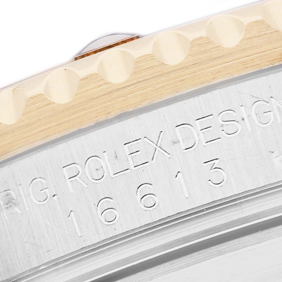 The image shows a close-up of the Rolex Submariner 16613 Men
s Steel and Gold (two tone) Blue Dial
s bezel edge and engraved model number on the case side.