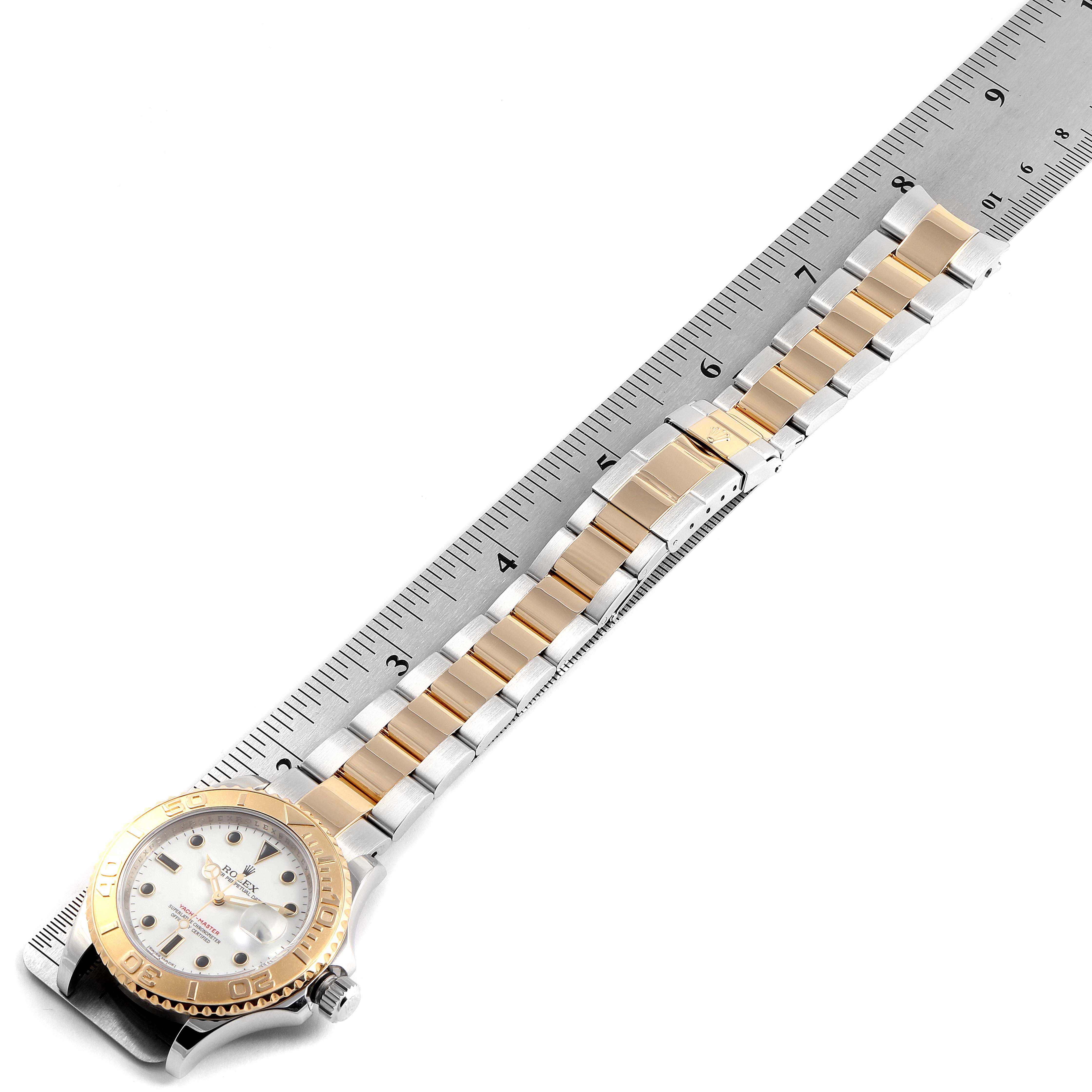 The Rolex Yacht-Master 16623 Men's Steel and Gold (two tone) White Dial 16623 Men's Steel and Gold (two tone) White Dial watch is shown lying flat with a ruler beside it, highlighting the dial, bezel, and bracelet.