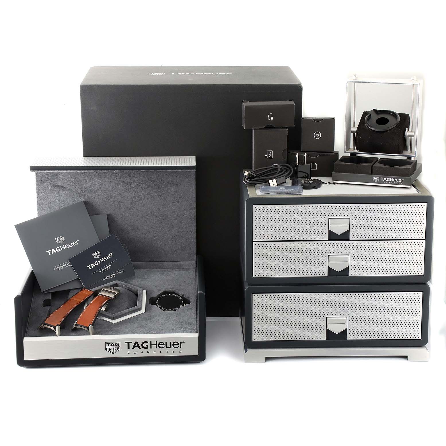 The image shows a set of accessories and packaging for the Tag Heuer Carrera ACBF5A80 Men's Titanium Black Dial ACBF5A80 Men's Titanium Black Dial model, including a box, additional straps, manuals, and storage drawers.