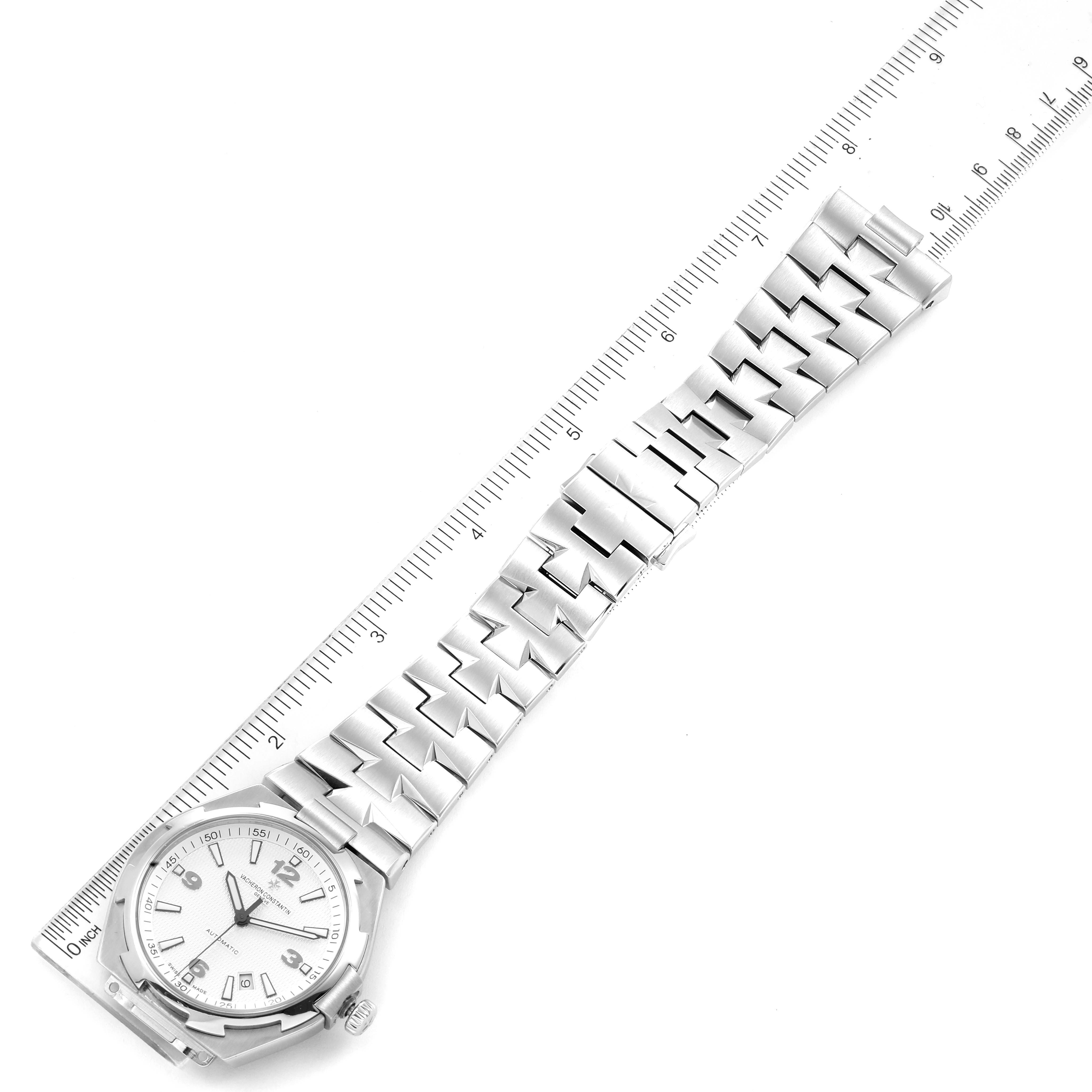 The image shows a Vacheron Constantin Overseas 47040B01A-9093 Men's Stainless Steel Silver Dial 47040B01A-9093 Men's Stainless Steel Silver Dial watch face and stainless steel bracelet viewed from a top-down angle beside a ruler.