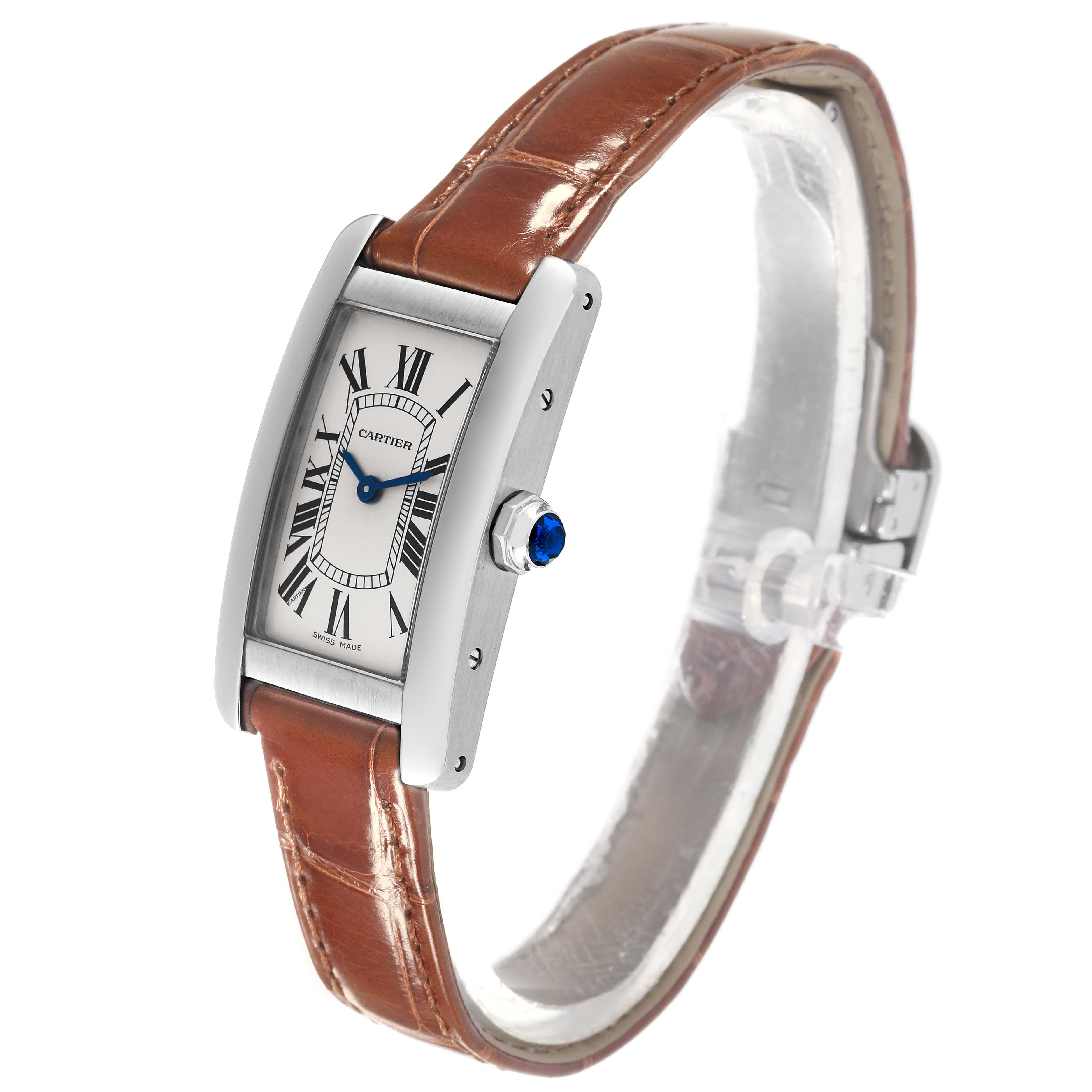 The image shows a side angle of the Cartier Tank Americaine WSTA0016 Women's Stainless Steel Silver Dial WSTA0016 Women's Stainless Steel Silver Dial watch, highlighting its rectangular face, leather strap, and crown with a blue gem.