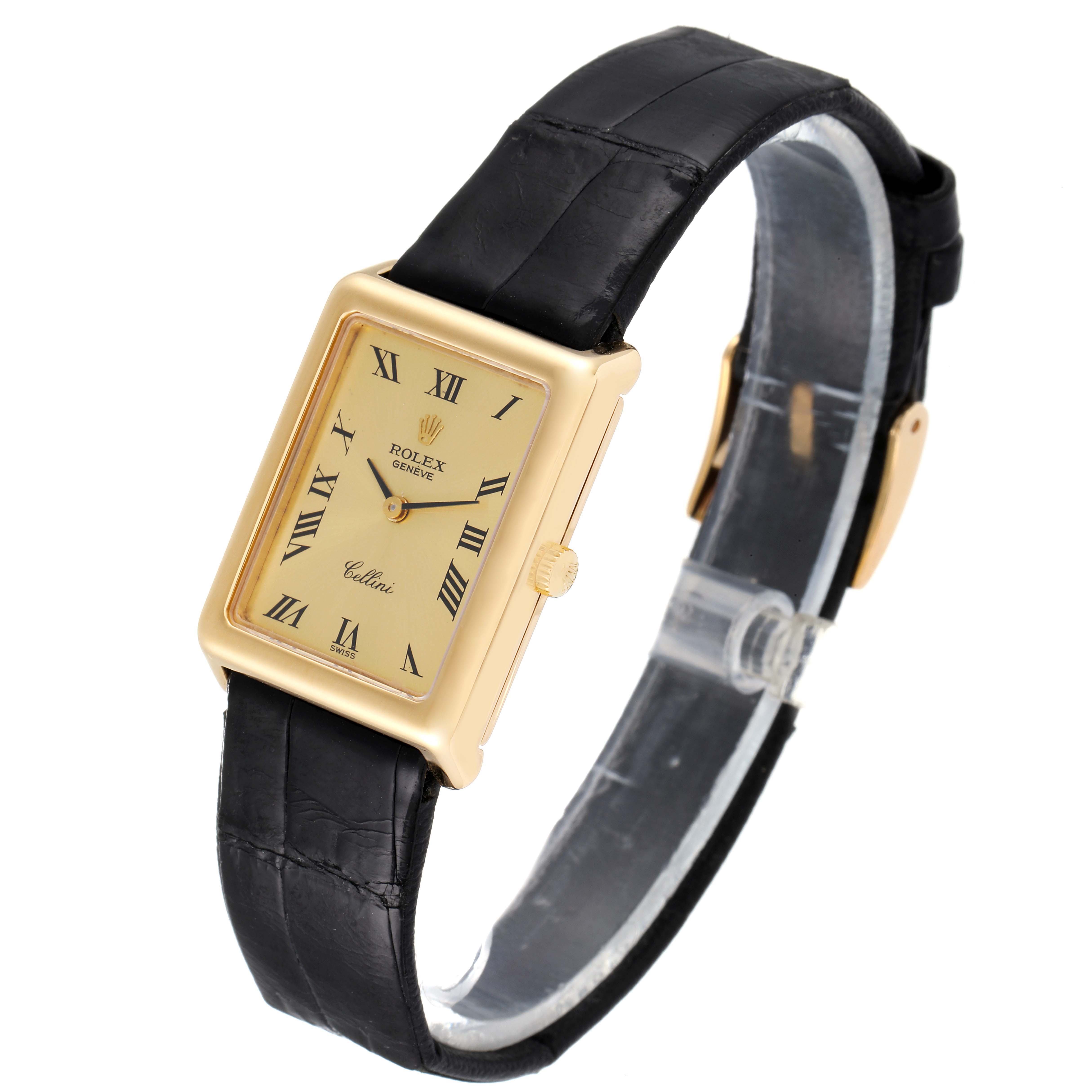 The Rolex Cellini 4103 Women's Yellow Gold Champagne Dial 4103 Women's Yellow Gold Champagne Dial watch is shown at a slight angle displaying its face, rectangular case, and black leather strap.