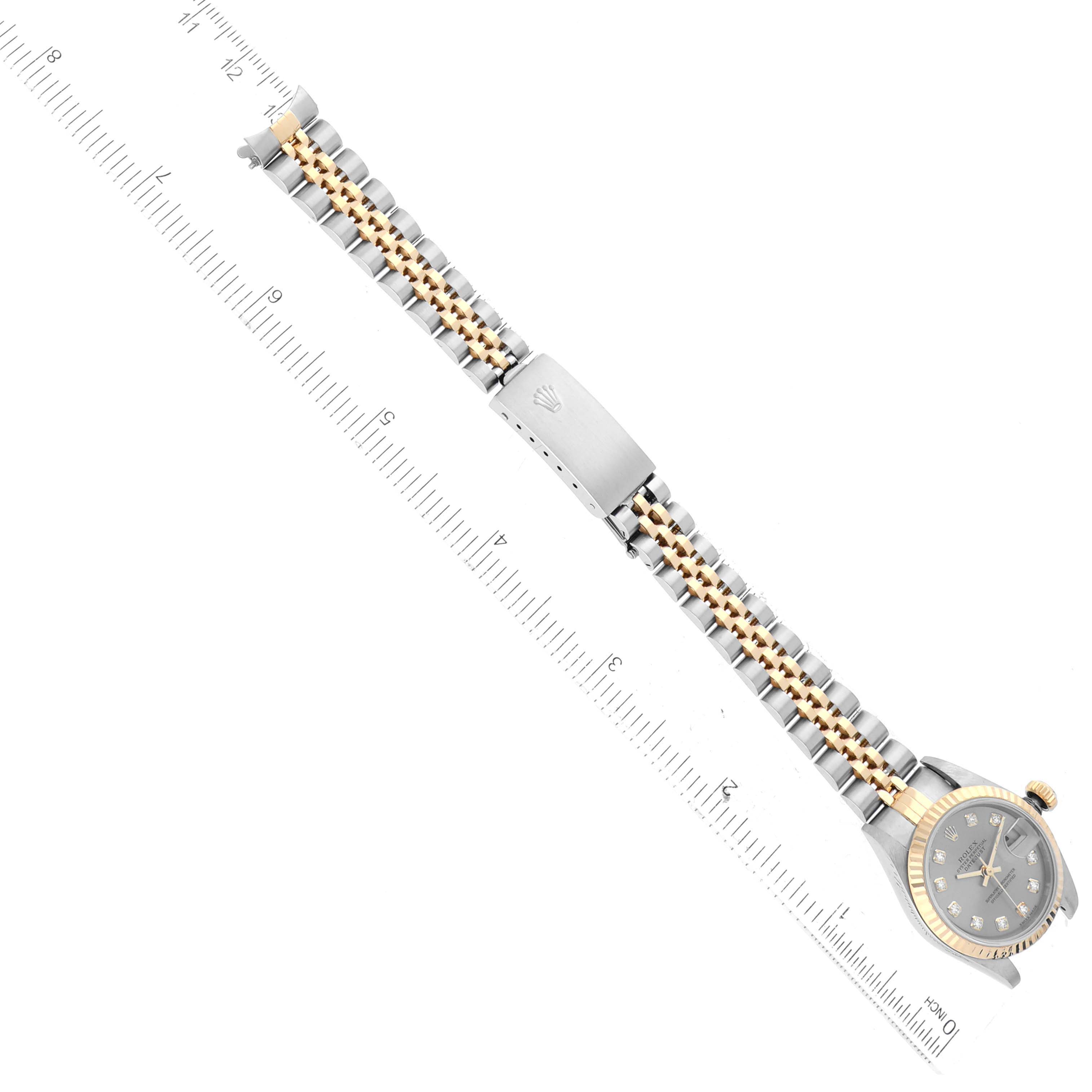 The image shows a Rolex Datejust 79173 Women's Steel and Gold (two tone) Silver Dial 79173 Women's Steel and Gold (two tone) Silver Dial watch laid flat with rulers on either side, displaying its bracelet and watch face.