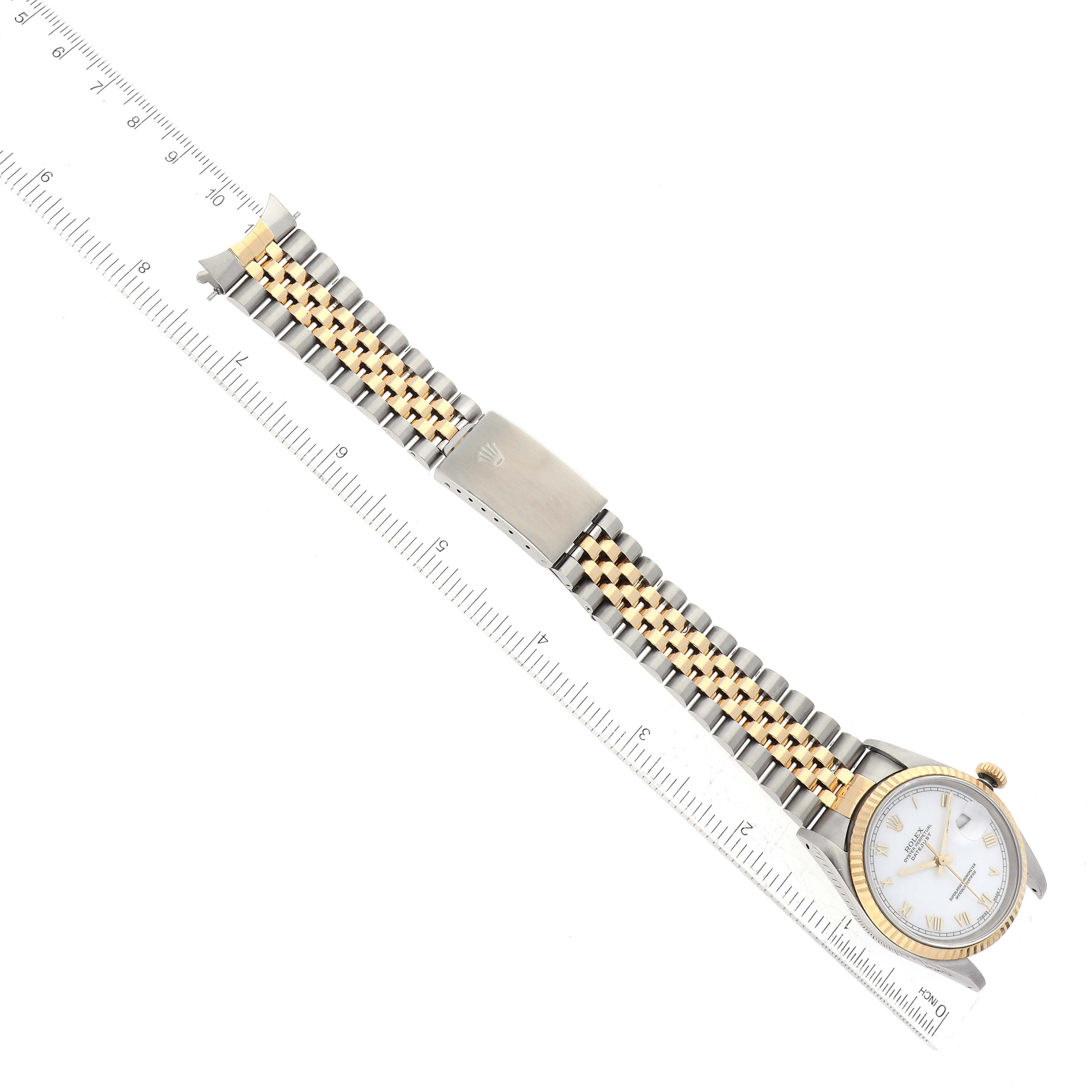 The Rolex Datejust 16233 Men's Steel and Gold (two tone) White Dial 16233 Men's Steel and Gold (two tone) White Dial watch is shown from an overhead angle, displaying its case, bracelet, and clasp alongside a ruler.