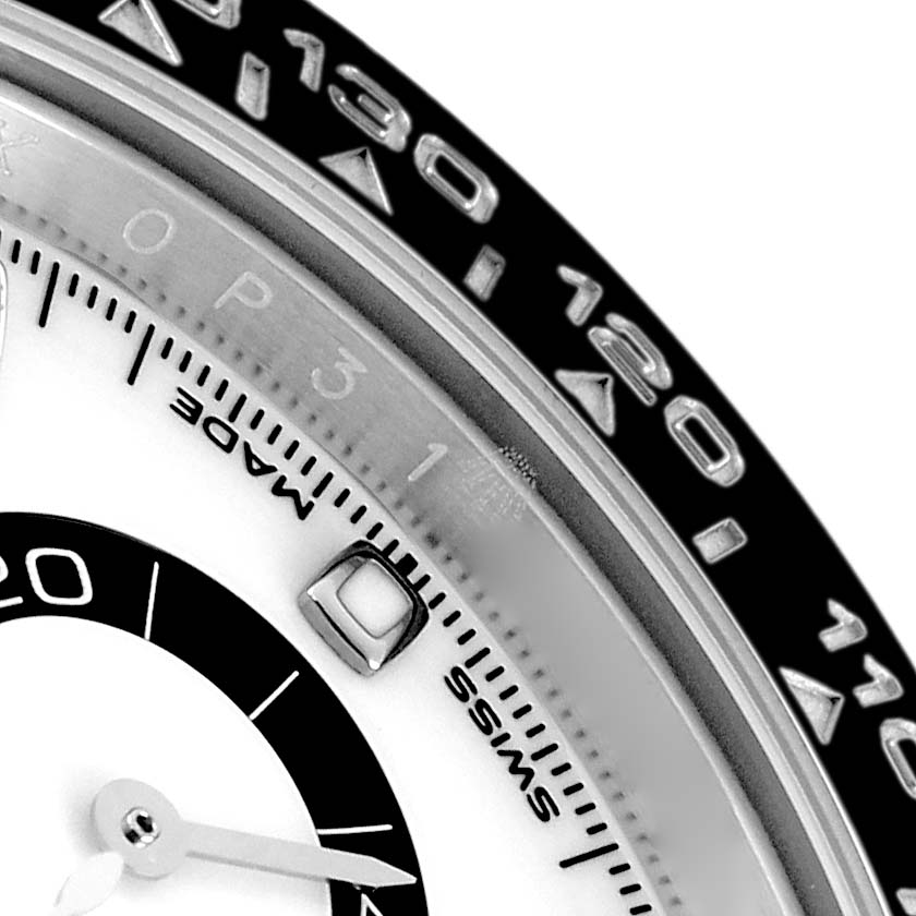 The image shows a close-up of a Rolex Daytona 116500 Men
s Stainless Steel White Dial watch, focusing on the bezel, part of the dial, and a subdial hand.