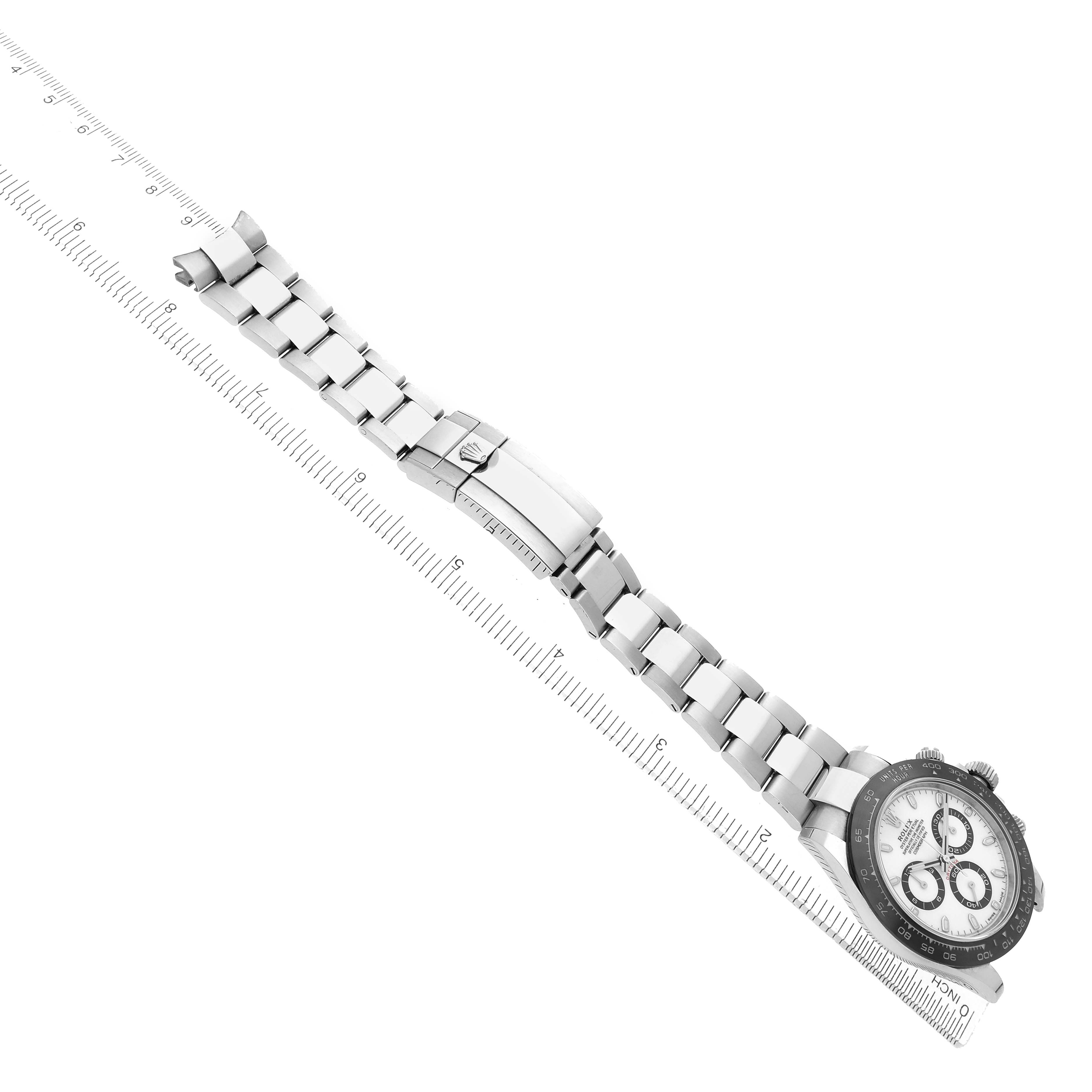 The Rolex Daytona 116500 Men
s Stainless Steel White Dial watch is shown from a top view with its bracelet fully extended alongside a measuring ruler.