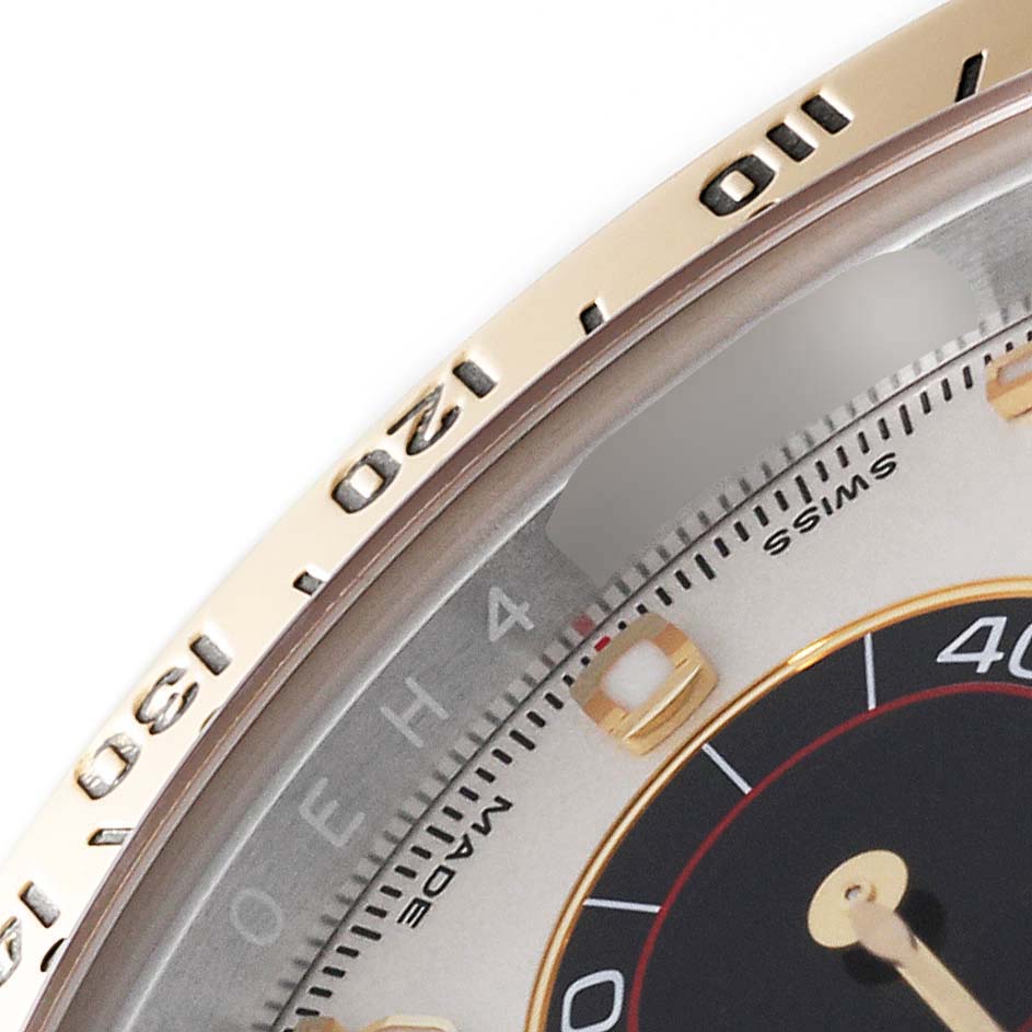 This close-up shows the bezel, part of the dial, and markers of a Rolex Daytona 116523 Men's Steel and Gold (two tone) Silver Dial 116523 Men's Steel and Gold (two tone) Silver Dial watch.