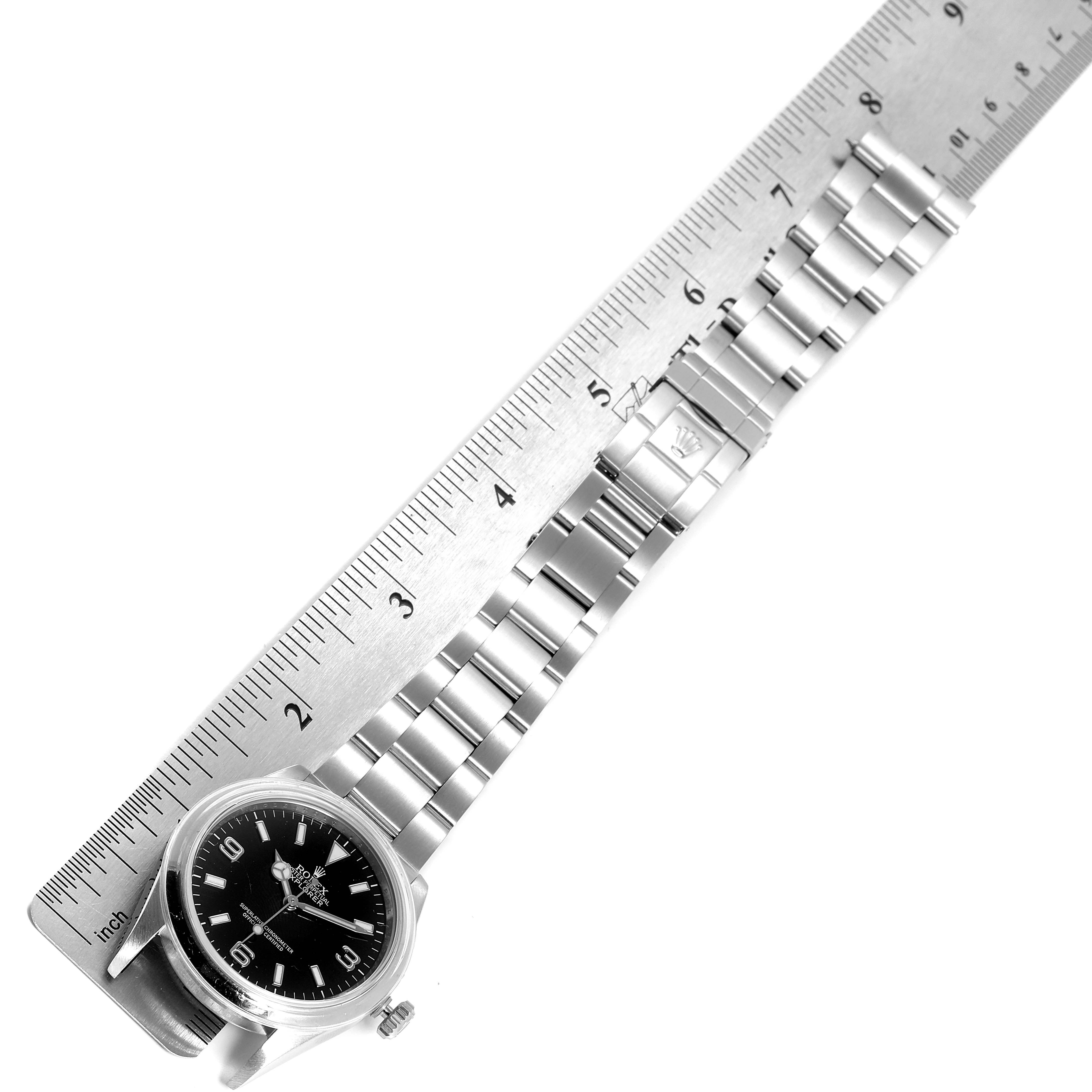 The image shows a Rolex Explorer 114270 Men's Stainless Steel Black Dial 114270 Men's Stainless Steel Black Dial watch laid next to a ruler, highlighting the wristband and face from an overhead angle.