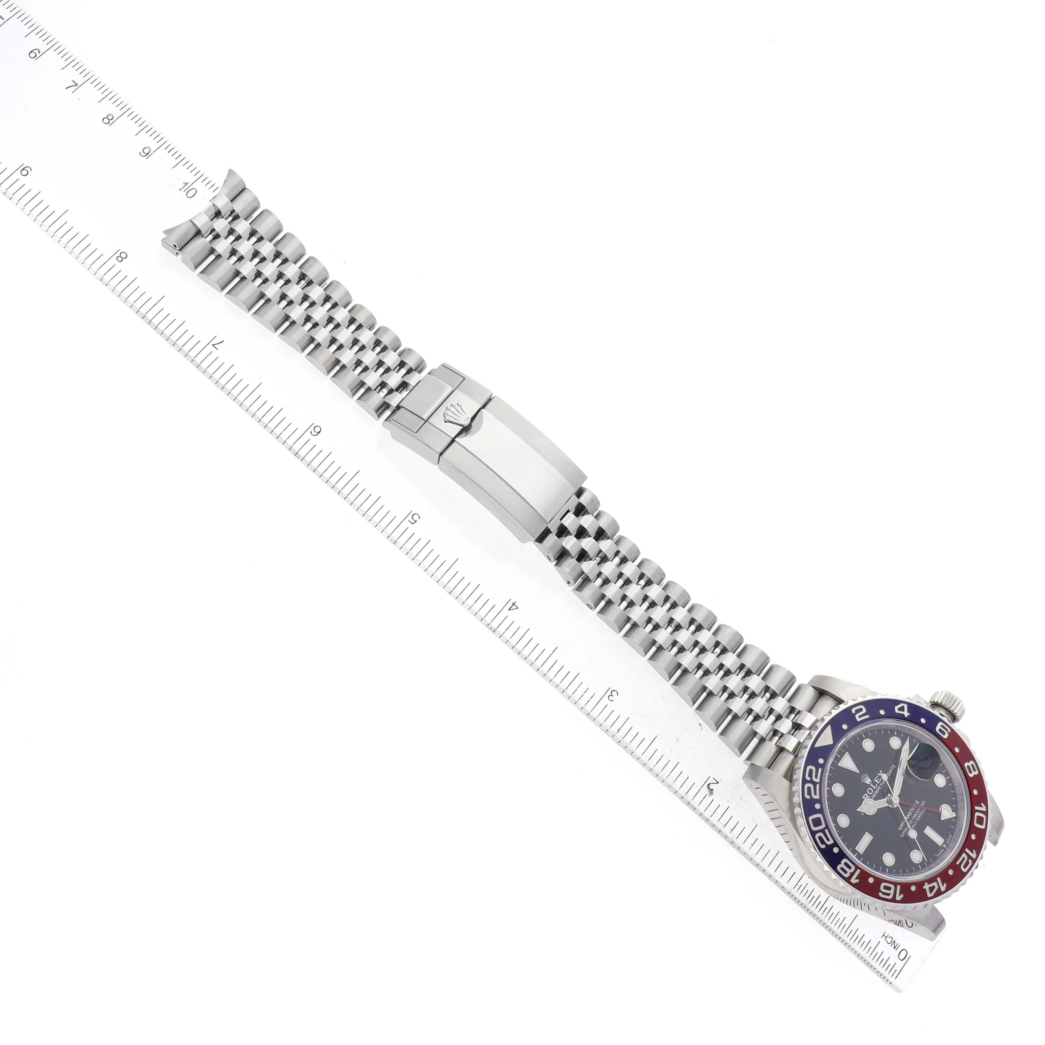 The image shows a Rolex GMT-Master 126710BLRO Men's Stainless Steel Black Dial 126710BLRO Men's Stainless Steel Black Dial watch and metal bracelet laid flat next to a ruler.