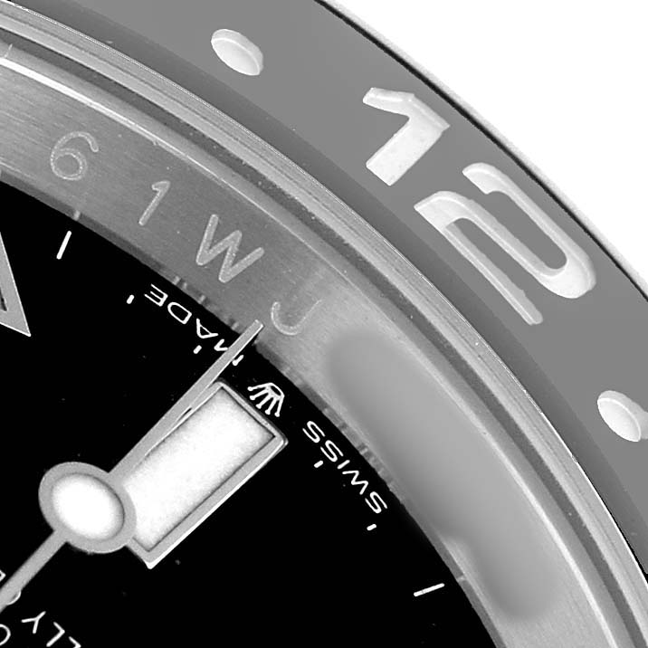 The image shows a close-up of the Rolex GMT-Master M126710GRNR Men's Stainless Steel Black Dial watch, focusing on the outer bezel and part of the dial, emphasizing the "12" marker.