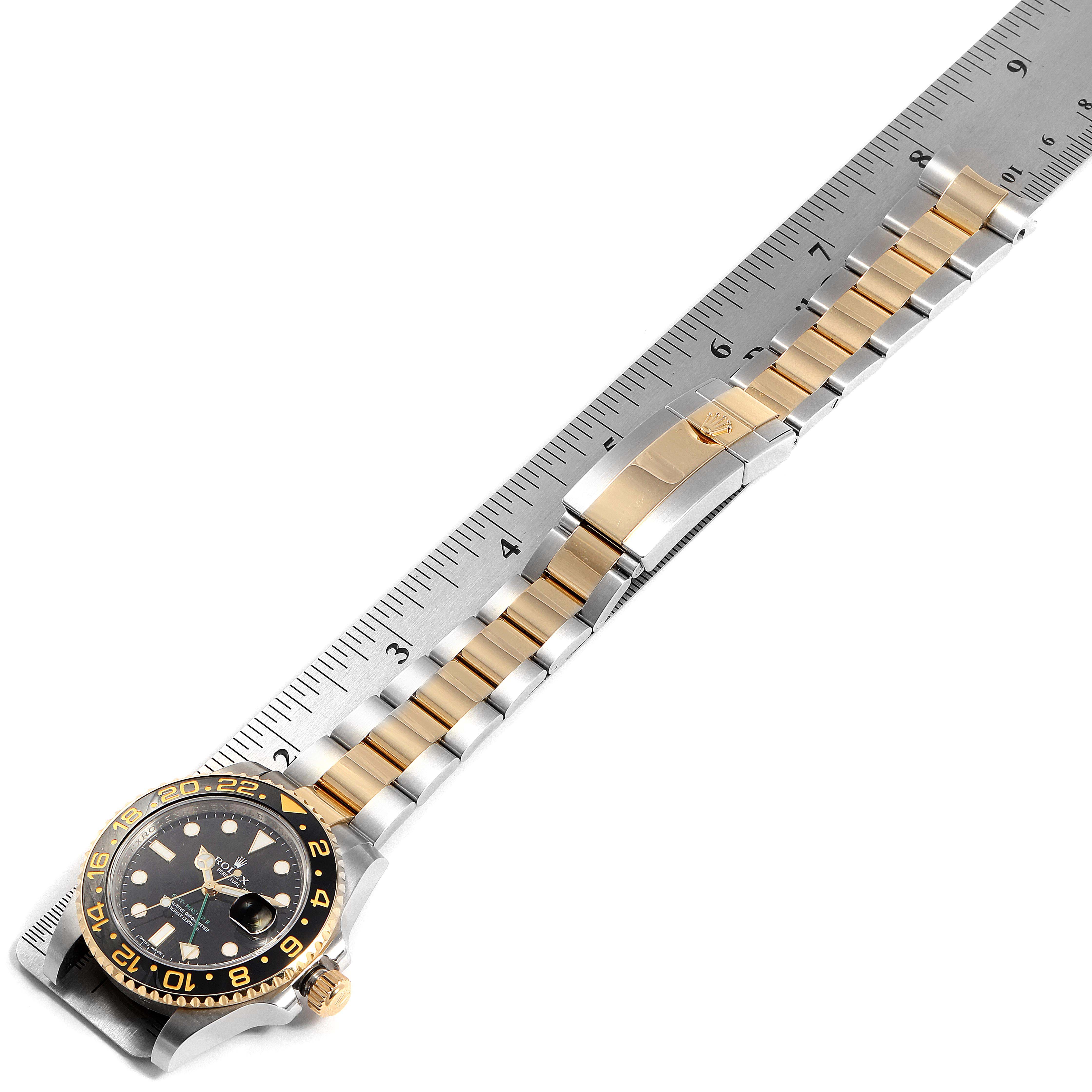 This image shows a Rolex GMT-Master 116713 Men's Steel and Gold (two tone) Black Dial 116713 Men's Steel and Gold (two tone) Black Dial watch laying flat with its dial, bezel, and full bracelet visible, aligned with a ruler.
