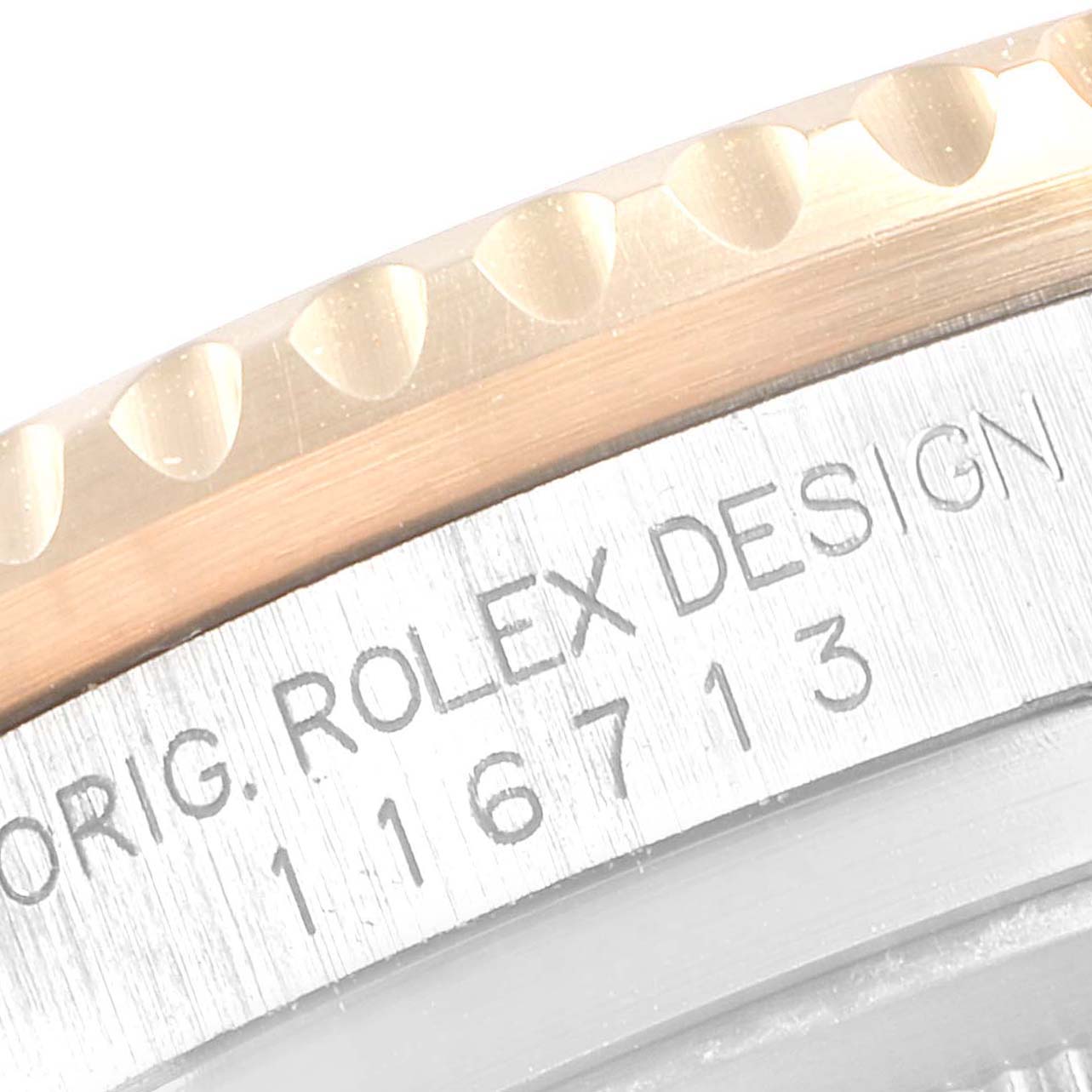 This close-up view of the Rolex GMT-Master 116713 Men's Steel and Gold (two tone) Black Dial 116713 Men's Steel and Gold (two tone) Black Dial watch shows a partial bezel and the engraved serial number on the case.