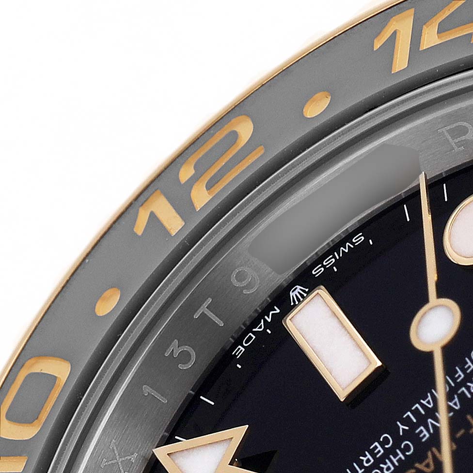 The image shows a close-up of the Rolex GMT-Master 126713GRNR Men's Steel and Gold (two tone) Black Dial bezel and part of the dial at an angle.