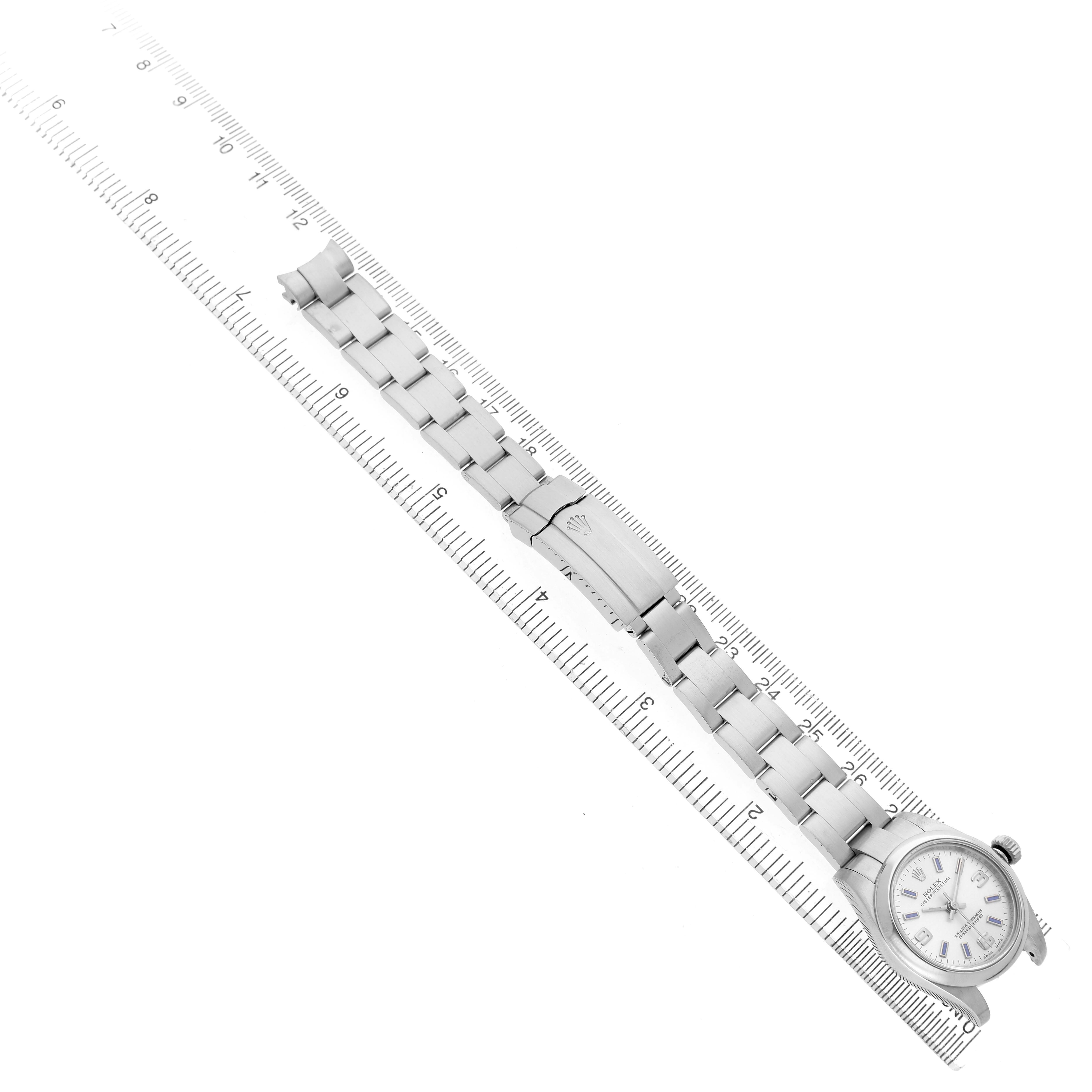 The Rolex Oyster Perpetual 176200 Women's Stainless Steel Silver Dial watch is displayed from a top-down angle, showing the full bracelet and clasp alongside a ruler for scale.