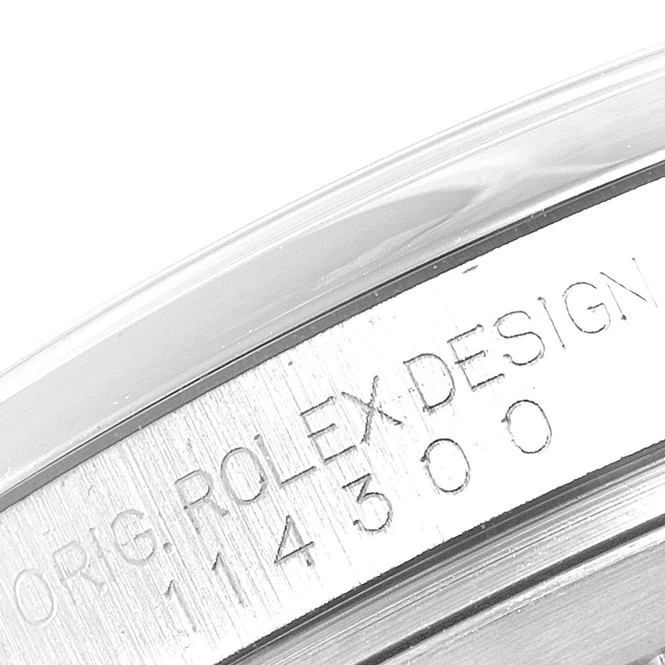 This image shows a close-up of the watch case engraving with the text "ORIG. ROLEX DESIGN" on the Rolex Oyster Perpetual 114300 Men's Stainless Steel Silver Dial 114300 Men's Stainless Steel Silver Dial model.