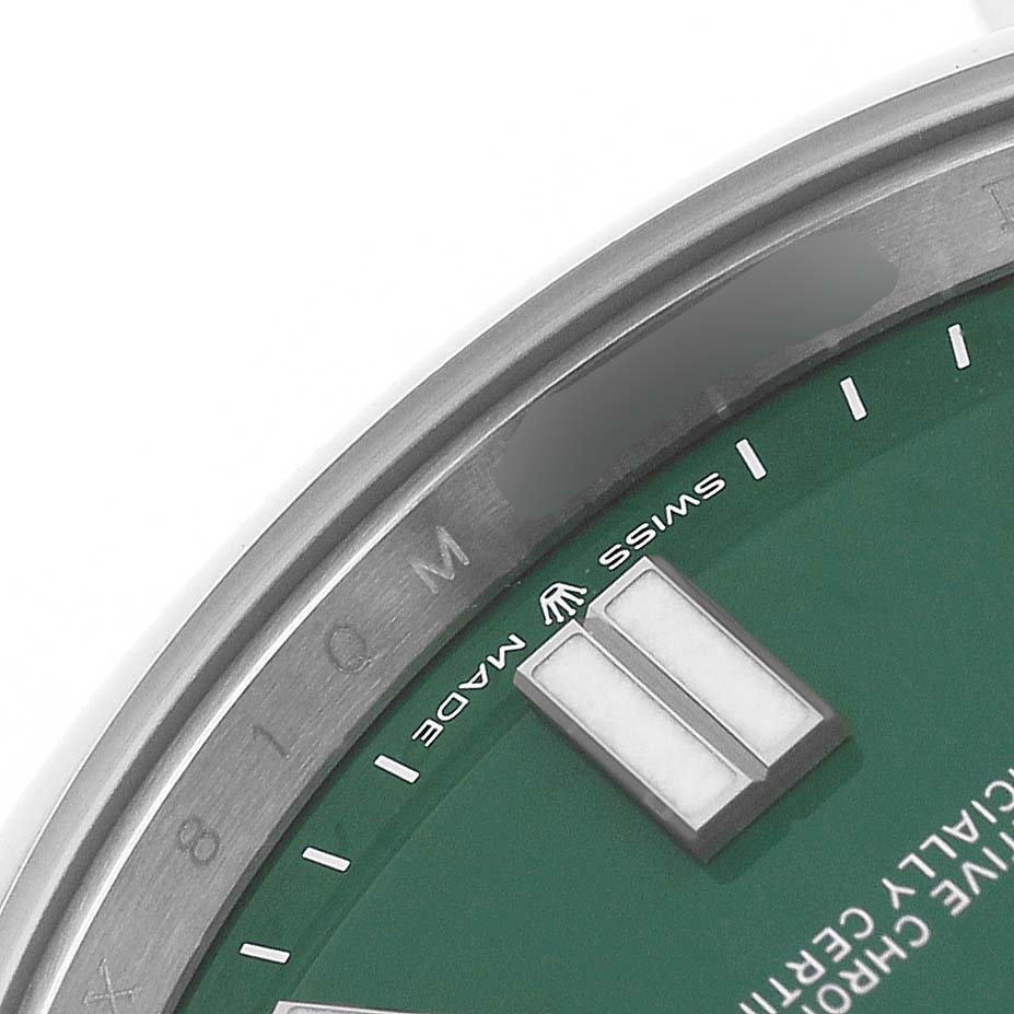 The image shows part of the dial, the bezel edge, and markers of a Rolex Oyster Perpetual 124300 Men's Stainless Steel Green Dial watch from a close-up angle.