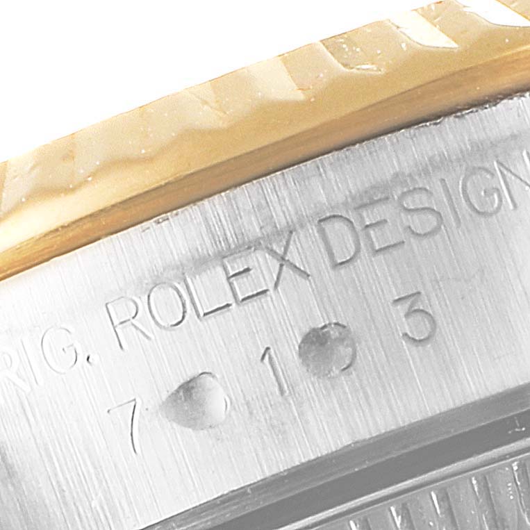 This close-up image shows the engraved serial number and part of the bezel of the Rolex Oyster Perpetual 76193 Women's Steel and Gold (two tone) Champagne Dial 76193 Women's Steel and Gold (two tone) Champagne Dial watch.