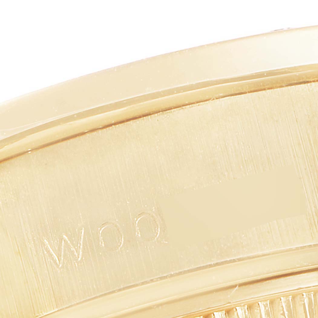 This close-up image of a Rolex President 69238 Women's Yellow Gold Silver Dial 69238 Women's Yellow Gold Silver Dial watch shows part of the bezel and case with engravings.