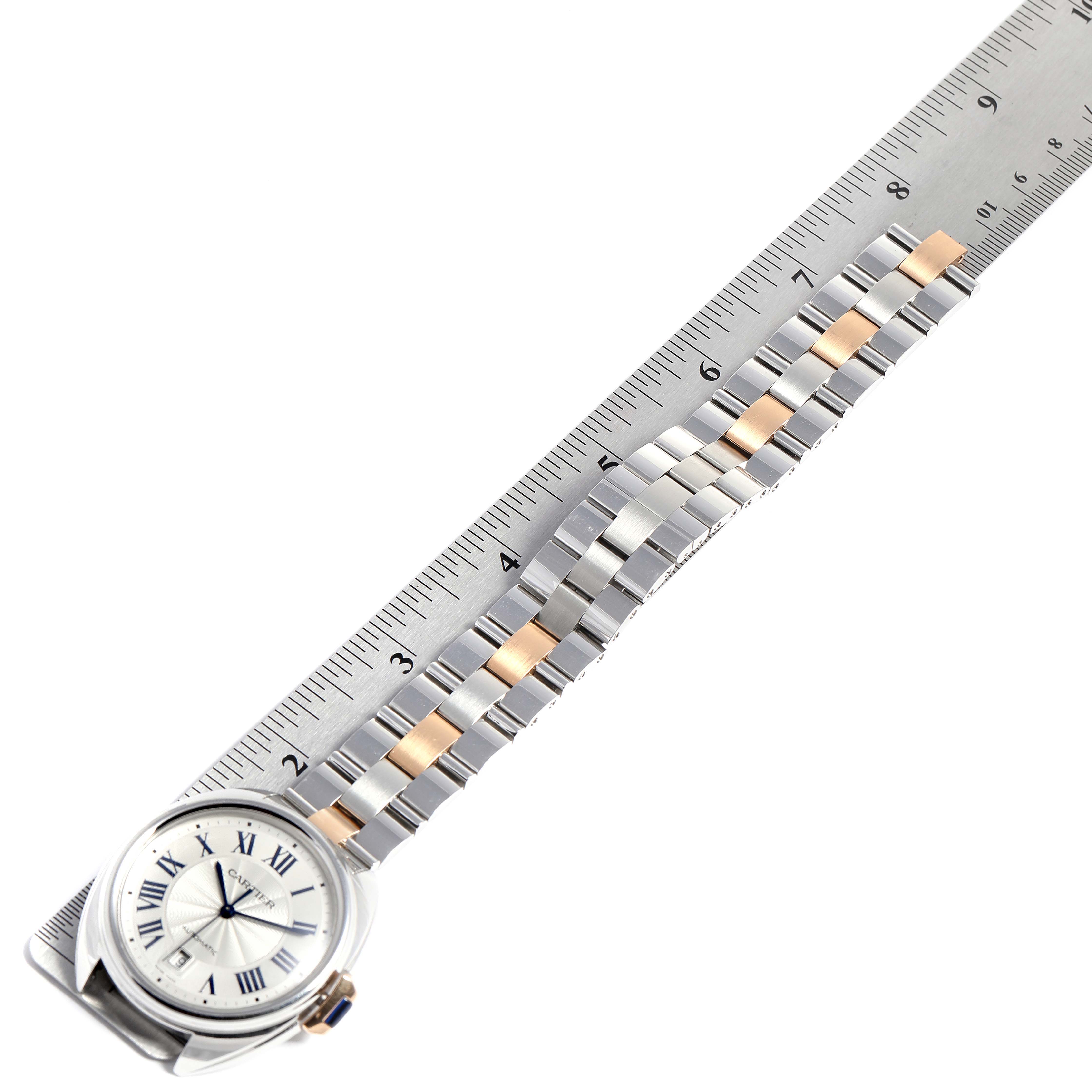 The image shows a Cartier Cle W2CL0002 Men's Steel and Gold (two tone) Silver Dial W2CL0002 Men's Steel and Gold (two tone) Silver Dial model watch laying flat with its band extended, alongside a ruler.