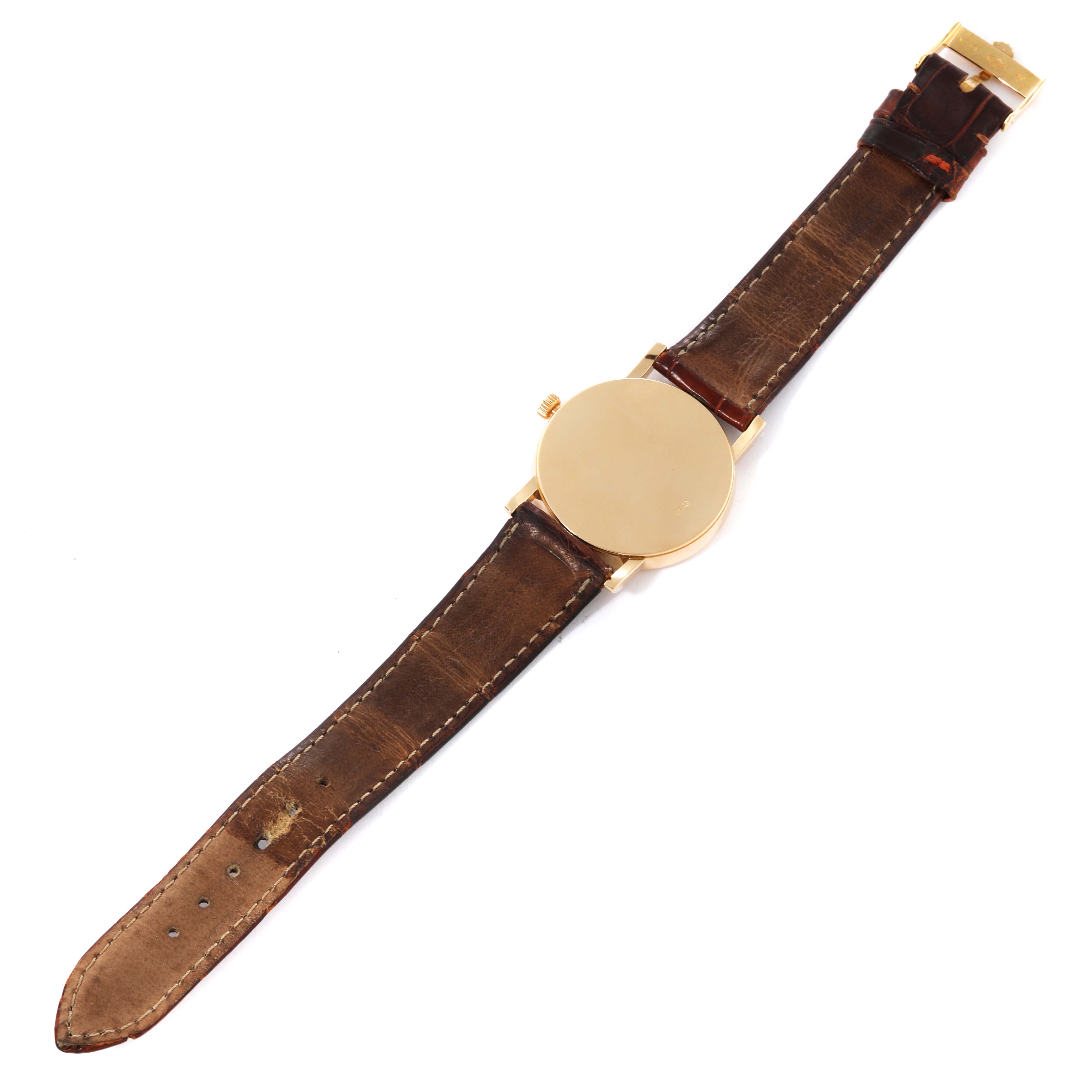 This image shows a top-down view of a Rolex Cellini 5115 Men's Yellow Gold Silver Dial 5115 Men's Yellow Gold Silver Dial watch, highlighting its leather strap and gold case back.