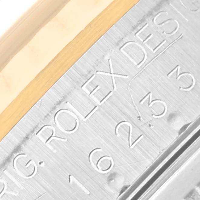 This image shows an extreme close-up of the engraved edge of a Rolex Datejust 16233 Men's Steel and Gold (two tone) Black Dial 16233 Men's Steel and Gold (two tone) Black Dial watch casing with serial numbers.