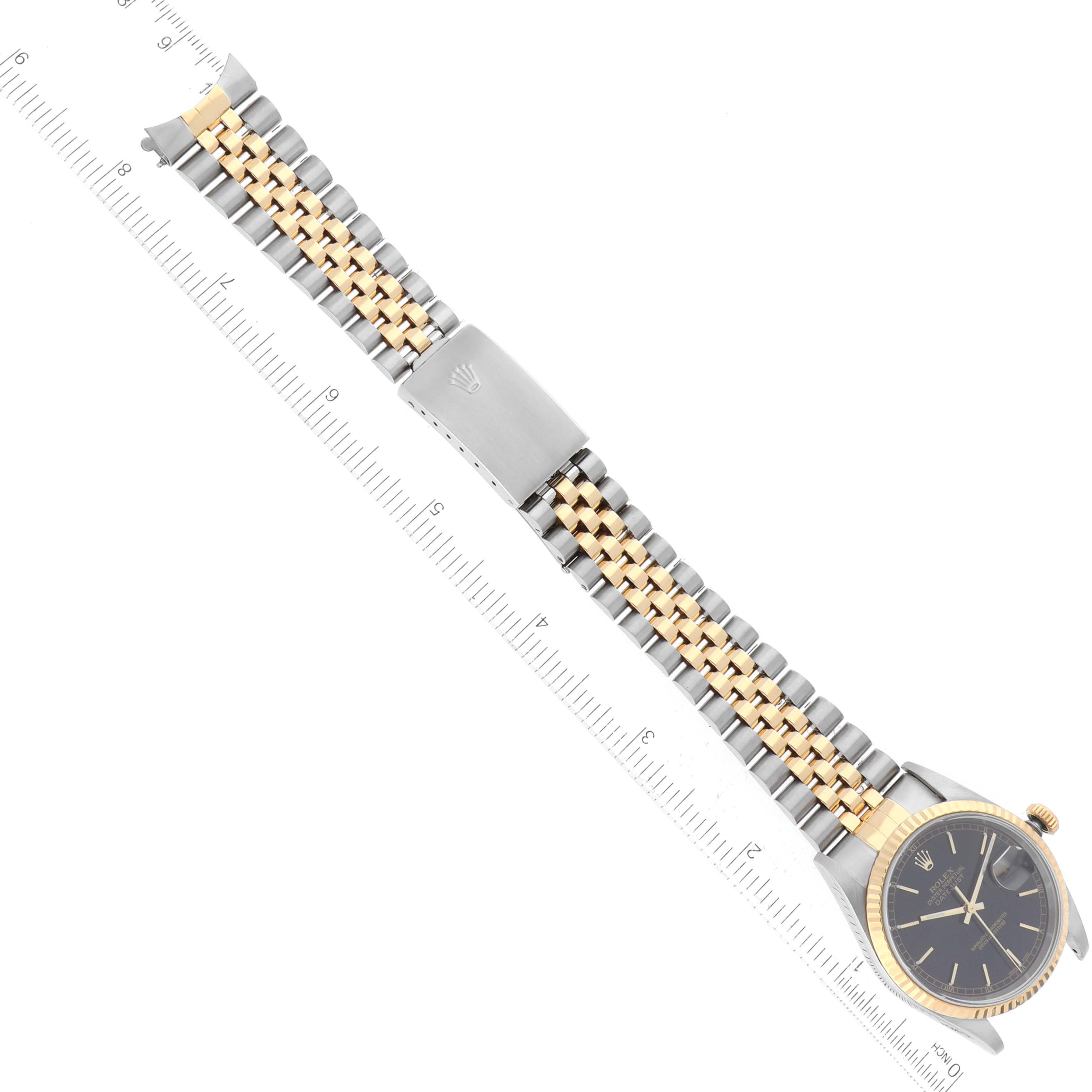 The image shows a Rolex Datejust 16233 Men's Steel and Gold (two tone) Black Dial 16233 Men's Steel and Gold (two tone) Black Dial watch, fully extended with its bracelet and clasp visible, alongside a ruler for scale.