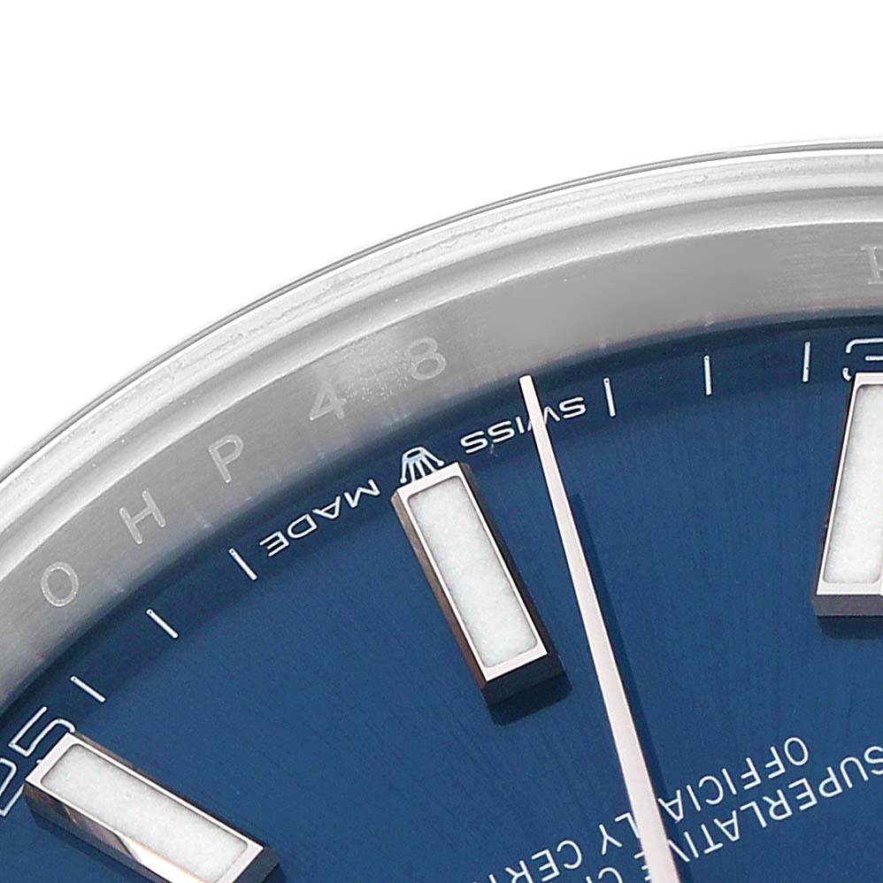The image shows a close-up of the Rolex Datejust 126300 Men
s Stainless Steel Blue Dial dial, focusing on the indices, hand, and bezel edge.