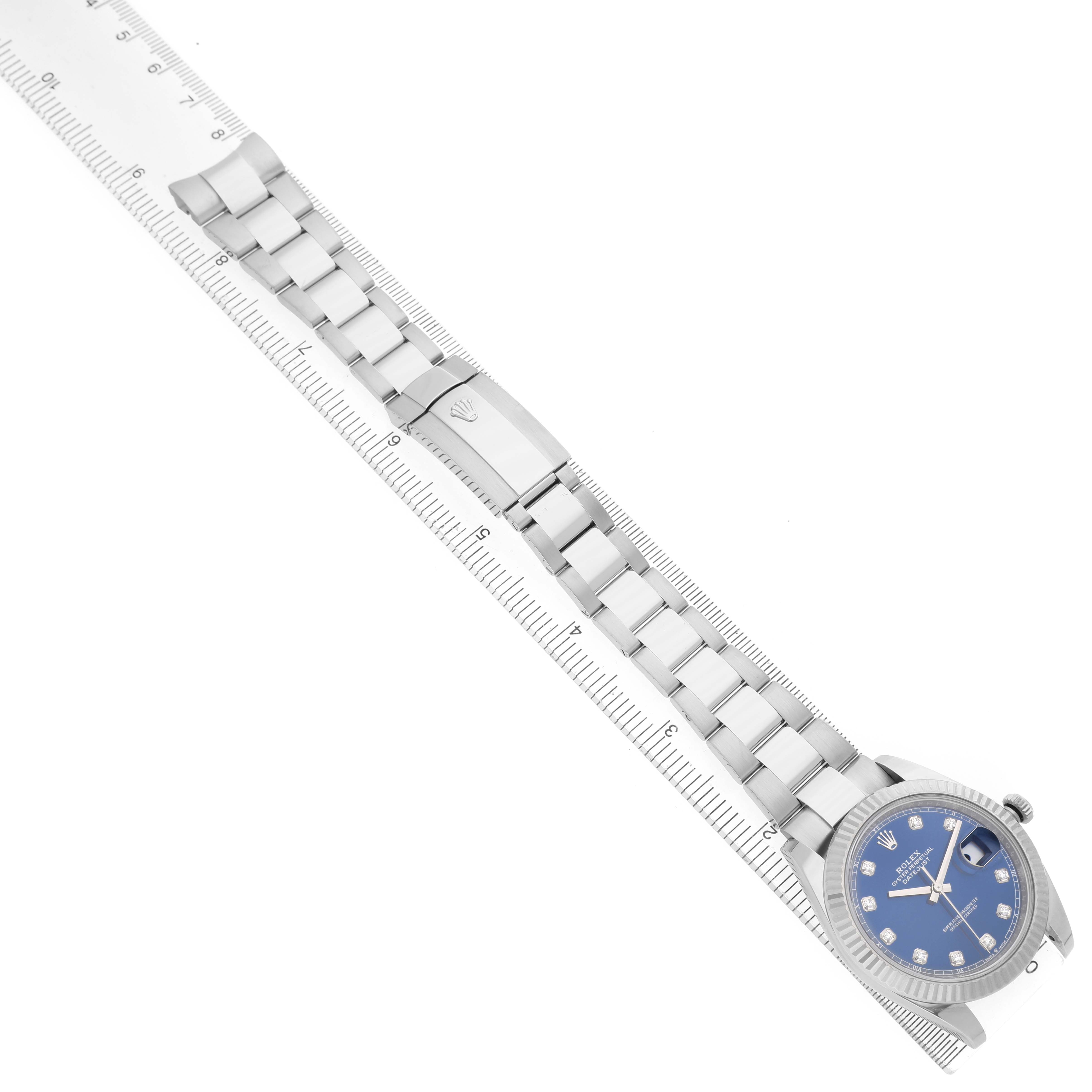 The Rolex Datejust 41 126334 Men's Steel and Gold (two tone) Blue Dial watch is shown from above with its full metal bracelet aligned with a ruler.