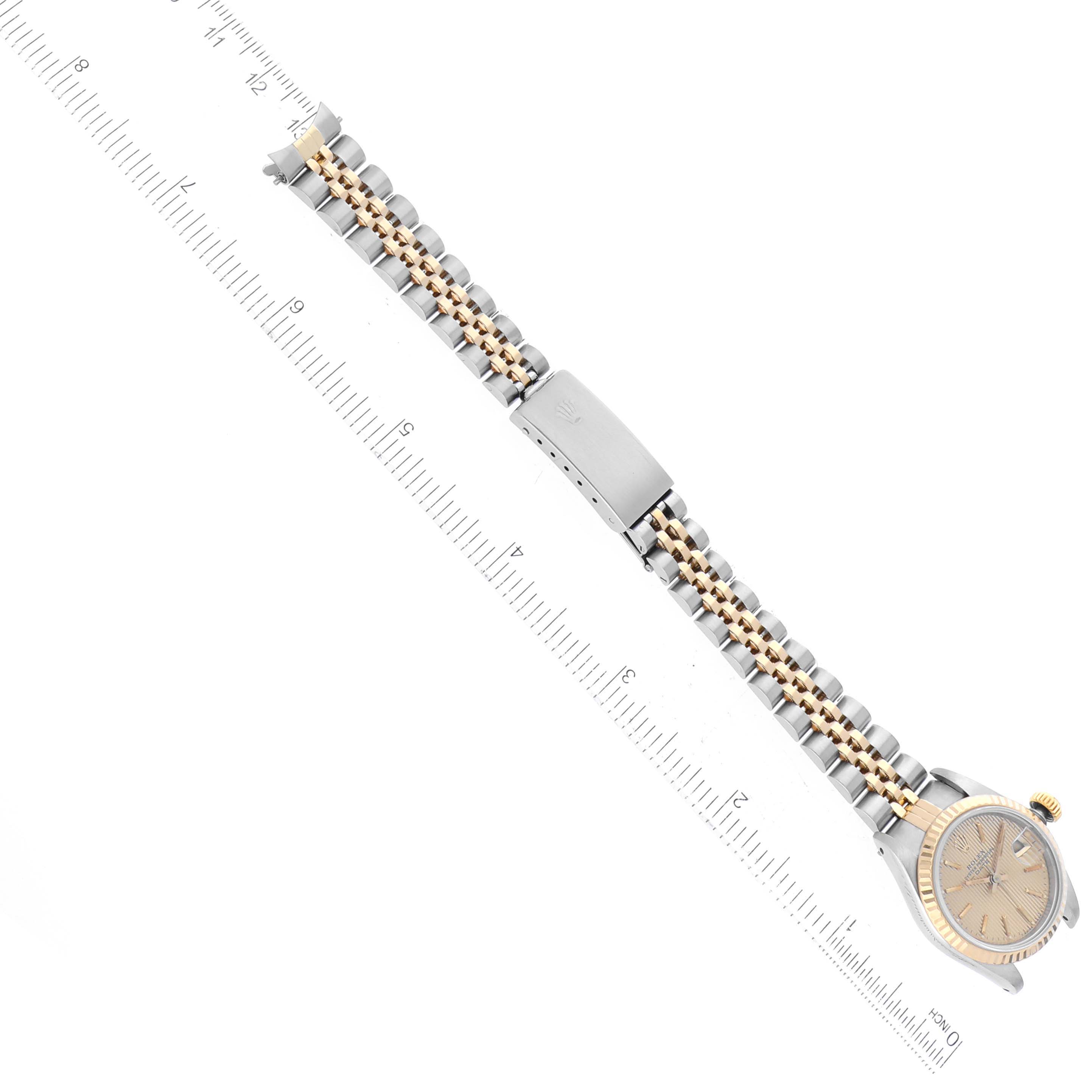 This image shows a Rolex Datejust 69173 Women's Steel and Gold (two tone) Champagne Dial 69173 Women's Steel and Gold (two tone) Champagne Dial watch from an angle displaying the full bracelet and clasp, aligned next to a ruler.