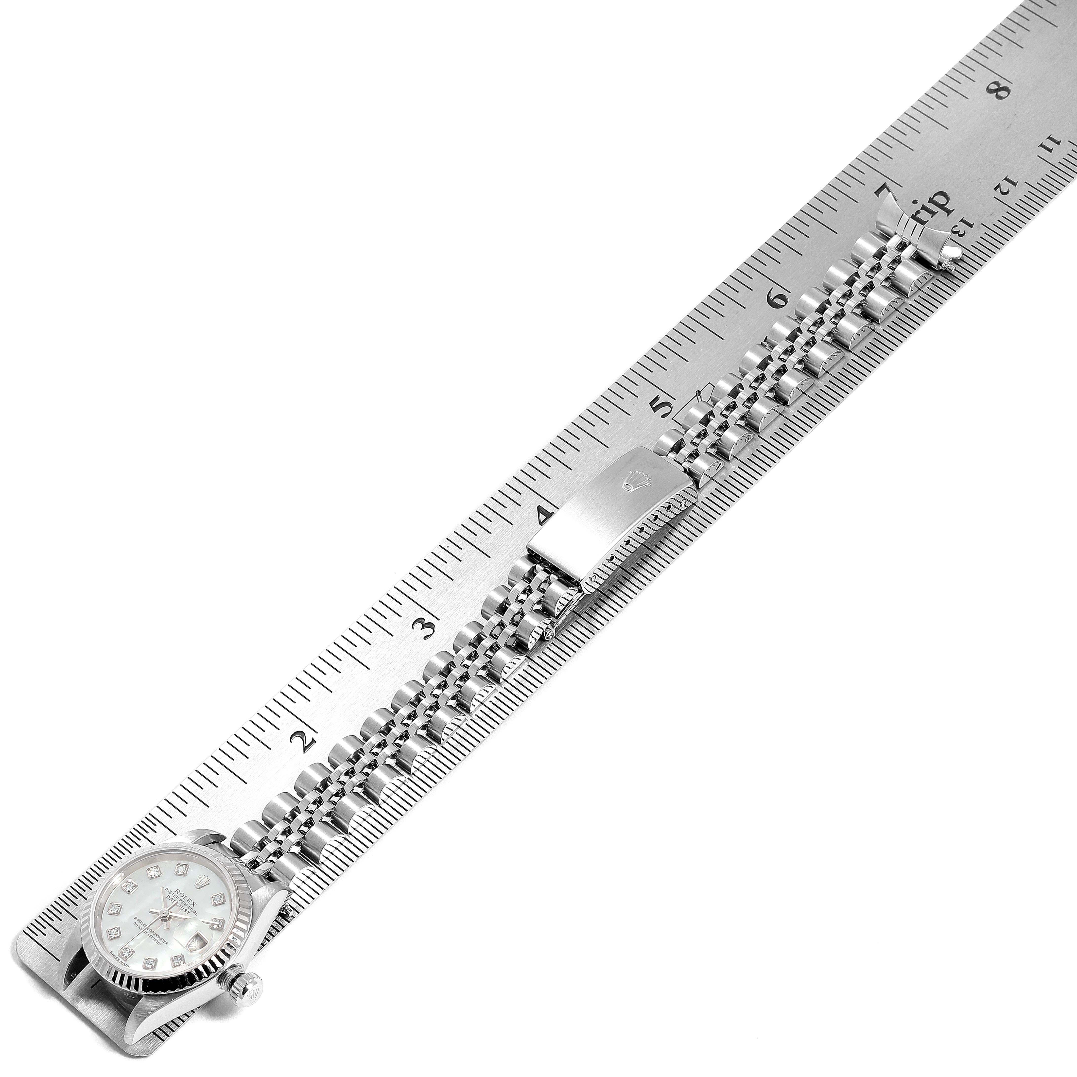 The Rolex Datejust 79174 Women
s Stainless Steel Mother of Pearl Dial 79174 Women
s Stainless Steel Mother of Pearl Dial watch is shown laid flat, alongside a ruler, displaying the face, crown, and bracelet with the clasp visible.