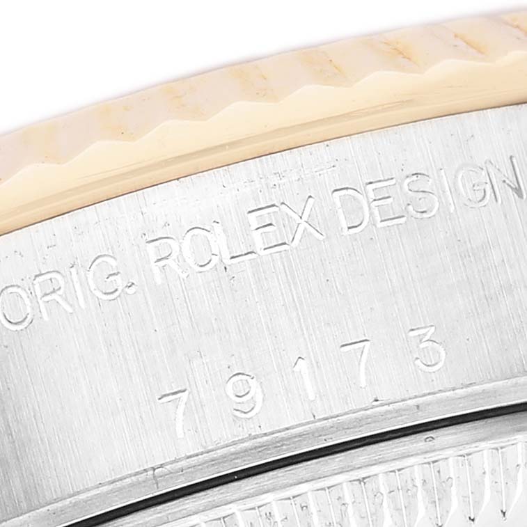 The image shows a close-up of the side of a Rolex Datejust 79173 Women's Steel and Gold (two tone) Champagne Dial watch case with engraved numbers and "ROLEX DESIGN".