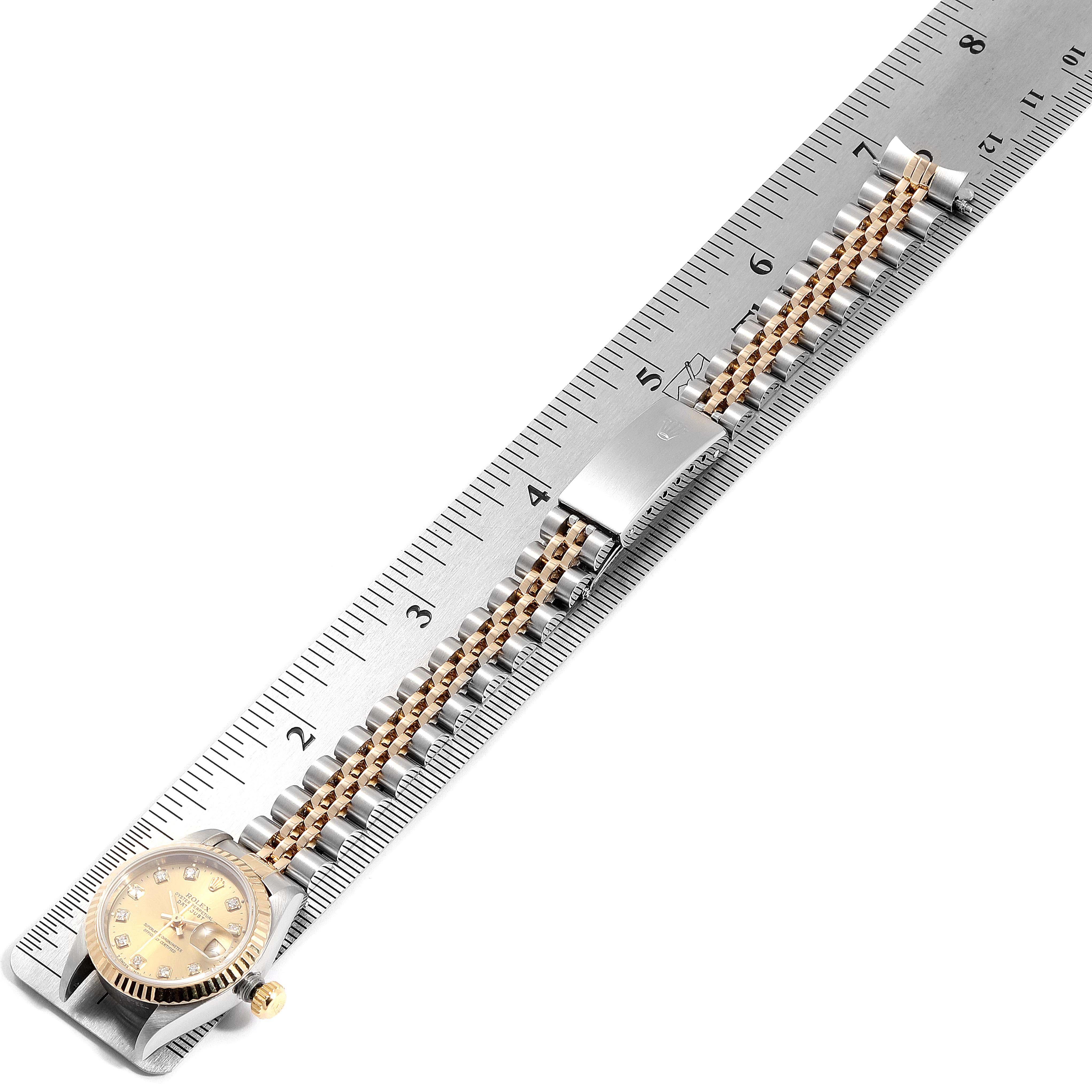 The image shows the Rolex Datejust 69173 Women
s Steel and Gold (two tone) Champagne Dial 69173 Women
s Steel and Gold (two tone) Champagne Dial model watch laid flat along a ruler, displaying the face, bracelet, and clasp from a top-down angle.