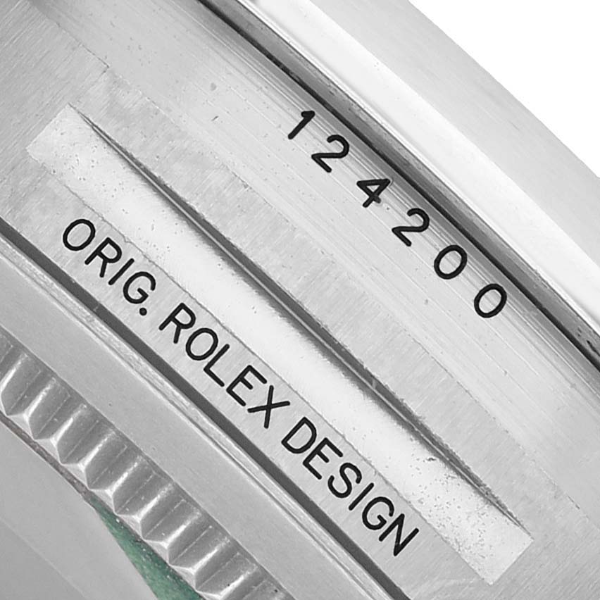 The image shows a close-up of the Oyster Perpetual Rolex case edge, highlighting the model number and "ORIG. ROLEX DESIGN" engraving.
