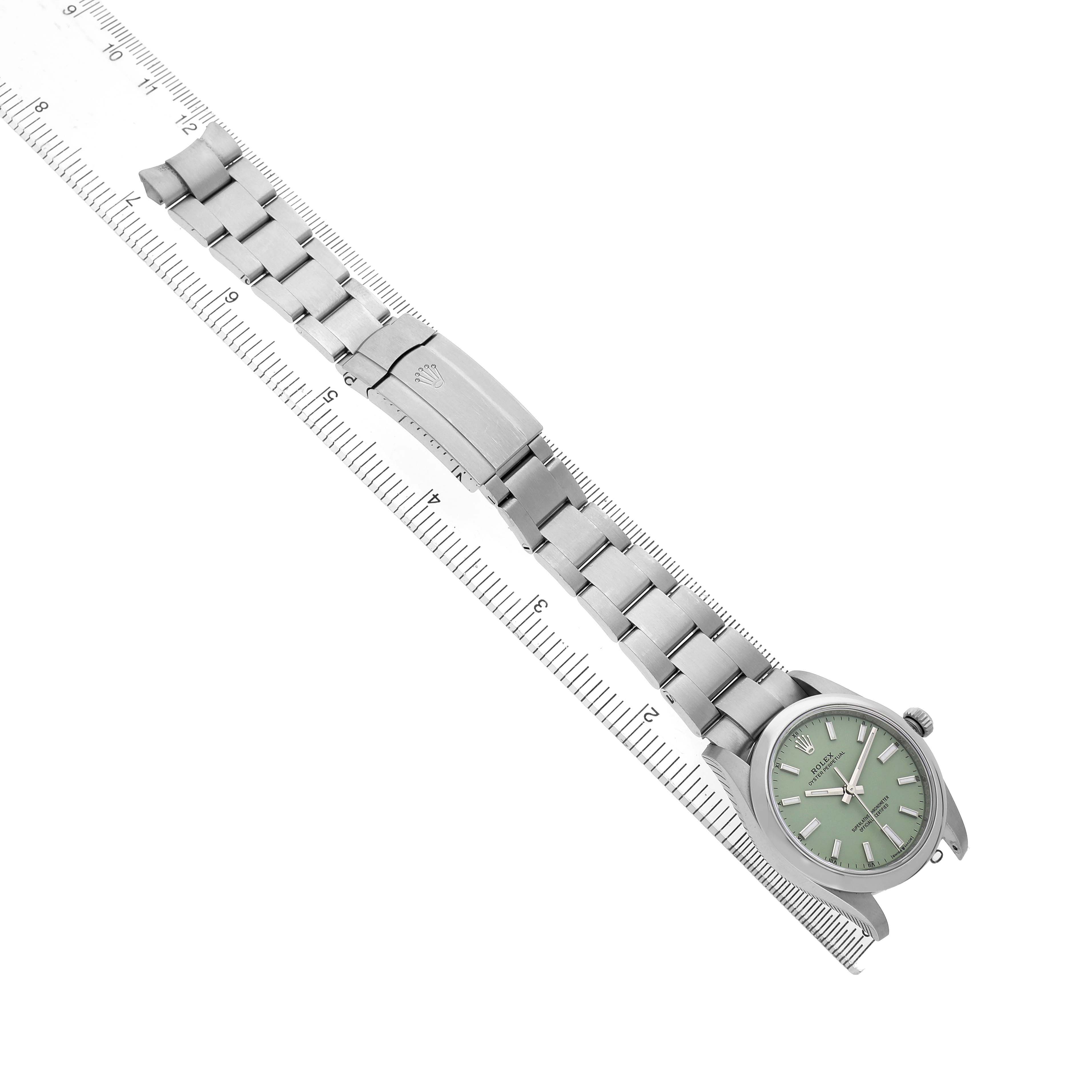 The Rolex Oyster Perpetual 124200 Men's Stainless Steel Green Dial watch is shown from an overhead angle, featuring its bracelet, clasp, and green dial.