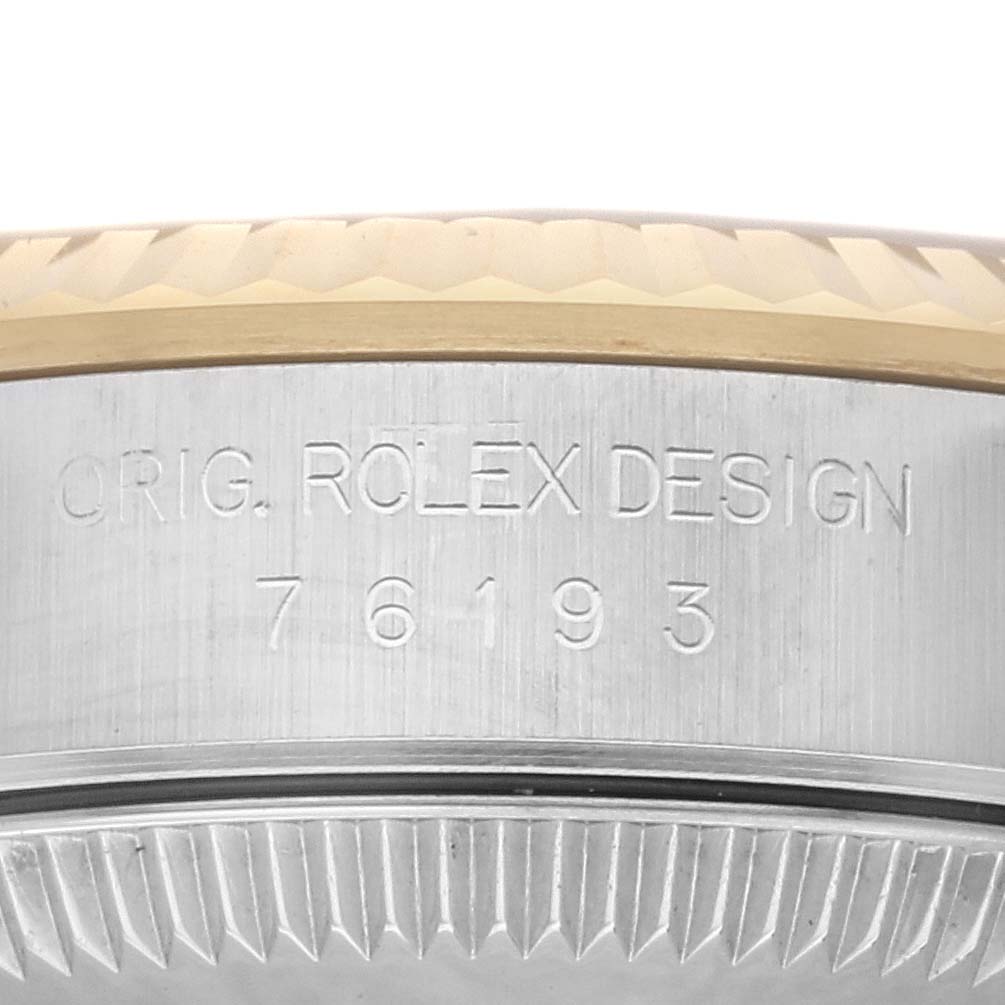 This image shows the side view of the casing of a Rolex Oyster Perpetual 76193 Women's Steel and Gold (two tone) Black Dial 76193 Women's Steel and Gold (two tone) Black Dial watch, displaying the model number 76193 and engraving.