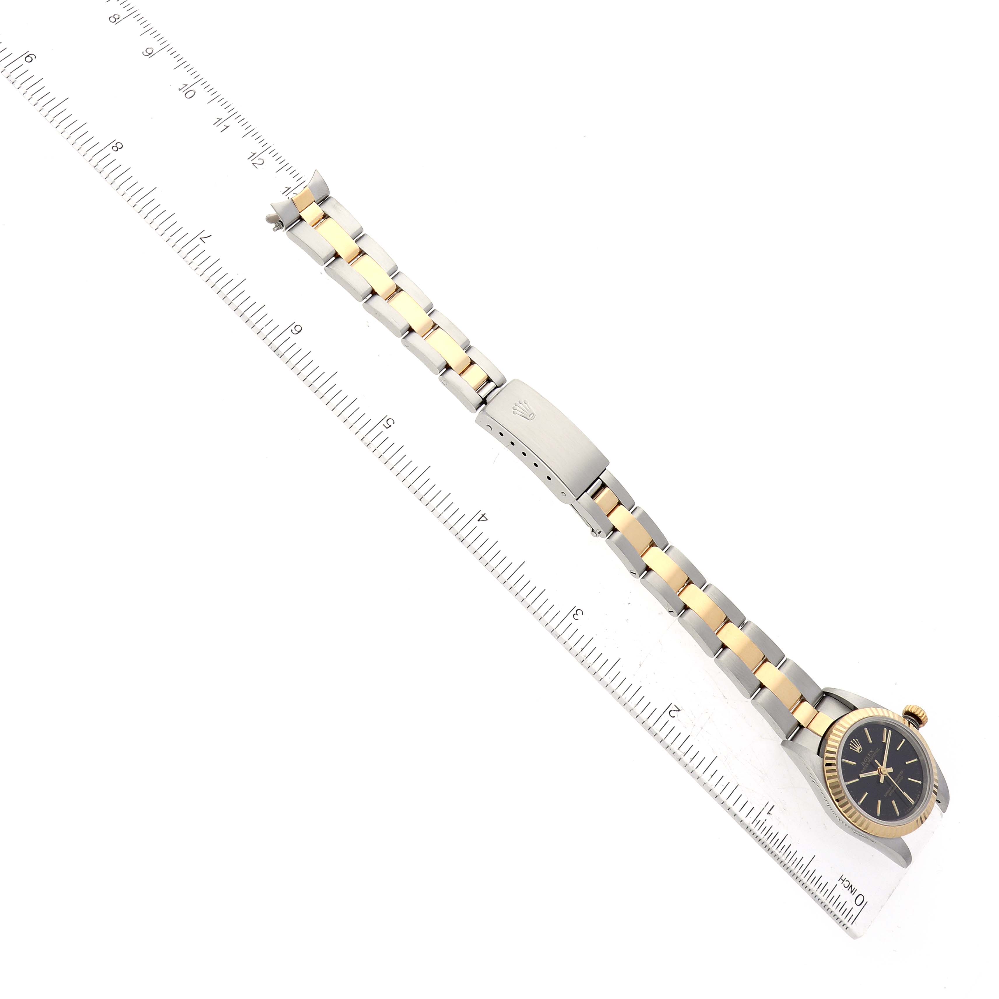 The image shows a side view of a Rolex Oyster Perpetual 76193 Women's Steel and Gold (two tone) Black Dial 76193 Women's Steel and Gold (two tone) Black Dial watch with a two-tone bracelet aligned beside a ruler for measurement.