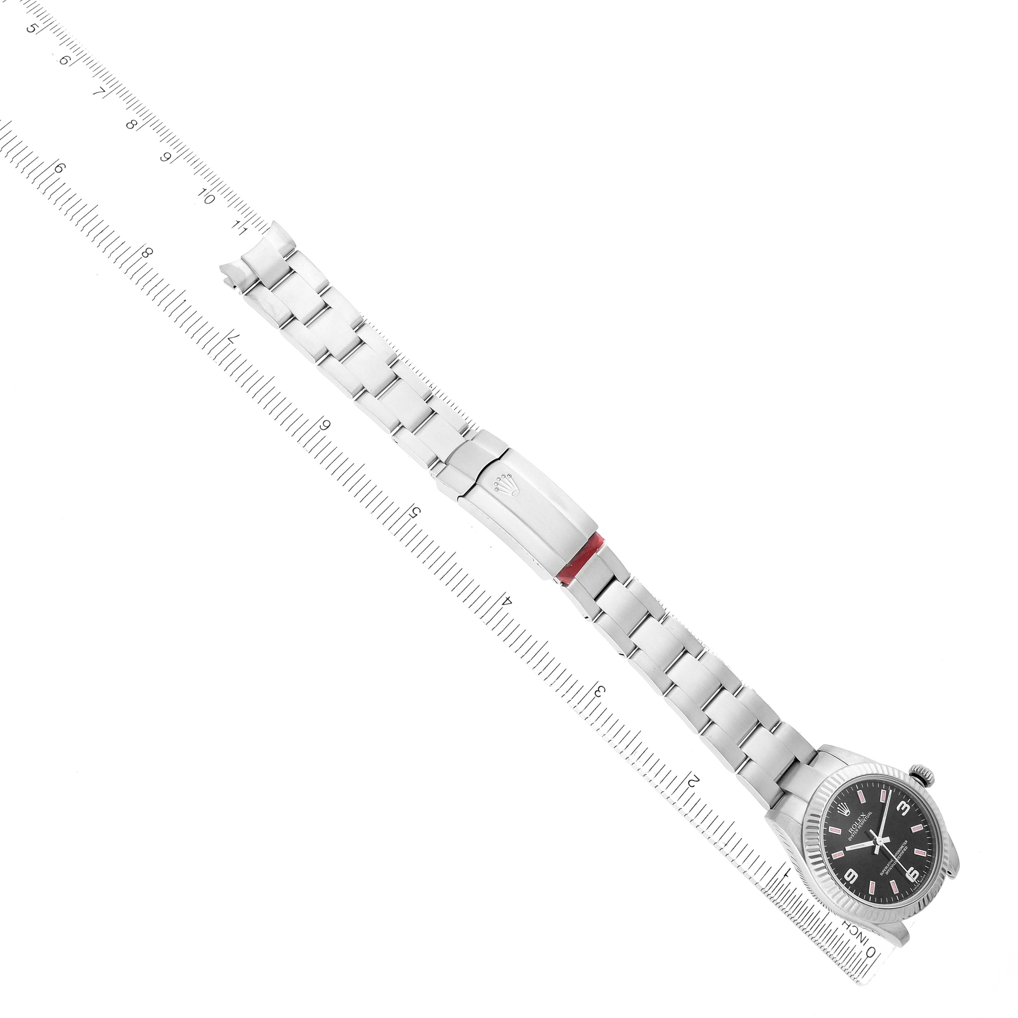 The Rolex Mid-Size 177234 Women
s Stainless Steel Black Dial watch is shown at an angle displaying the bracelet, clasp, and the full face alongside a ruler.