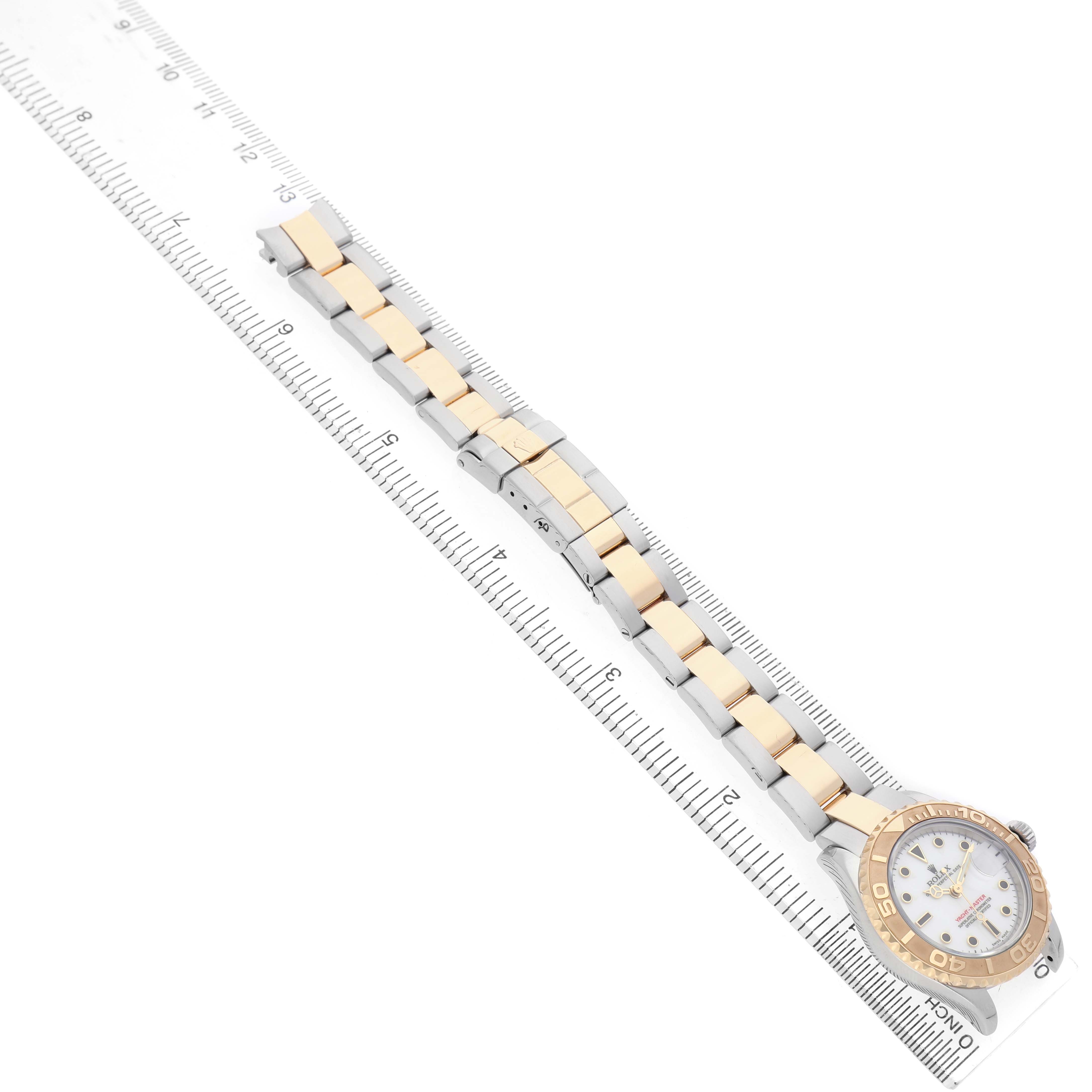 The Rolex Yacht-Master 169623 Women's Steel and Gold (two tone) White Dial watch is shown from an aerial angle, displaying its bracelet and face on a ruler for measurement.