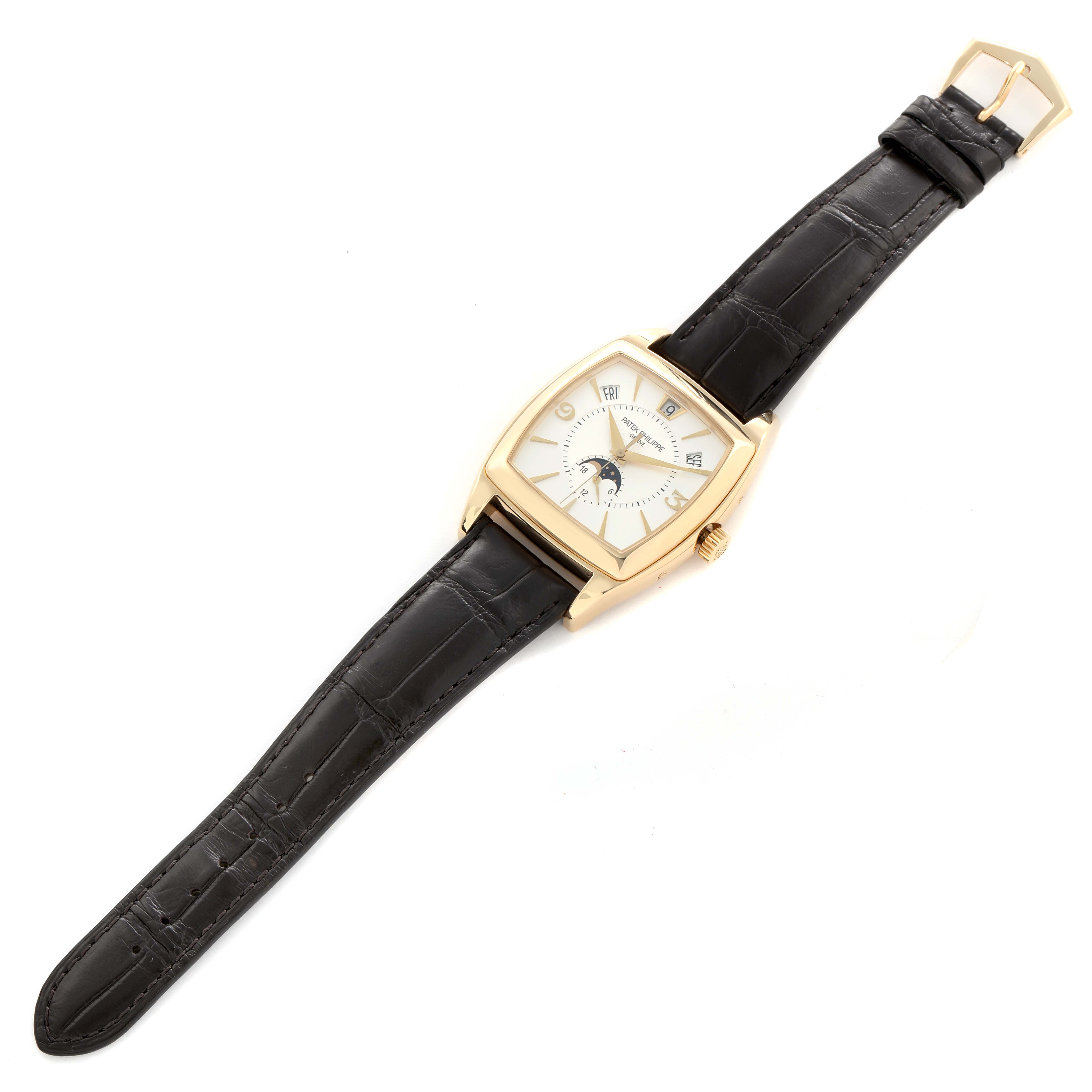 The Patek Philippe Gondolo 5135J Men
s Yellow Gold White Dial watch is shown from an overhead angle, featuring a square face, gold case, and black leather strap.