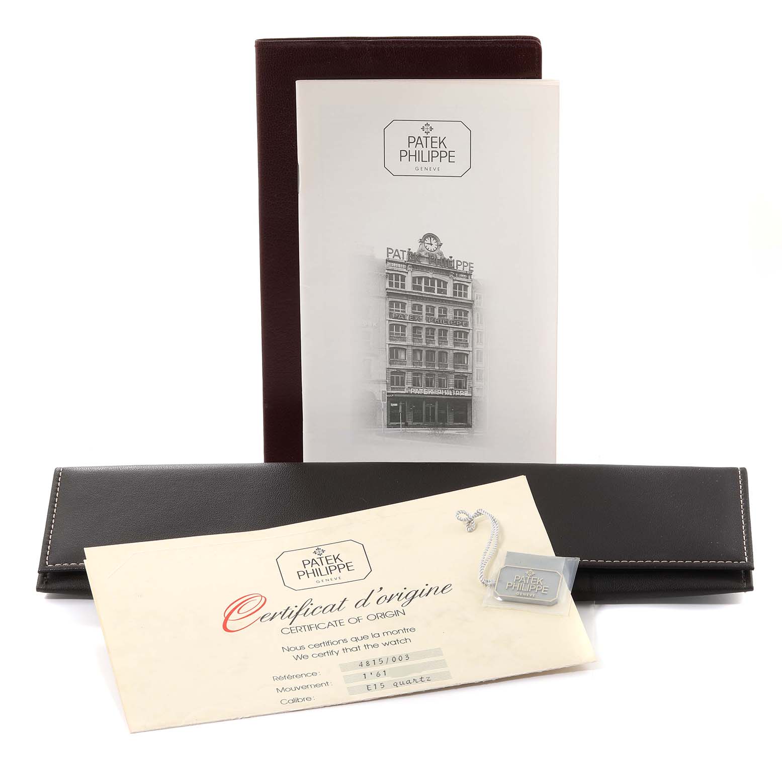 The image shows the Patek Philippe La Flamme  4815/003 Women's Yellow Gold Silver Dial 4815/003 Women's Yellow Gold Silver Dialmodel's certificate of origin, tag, and a leather document holder.