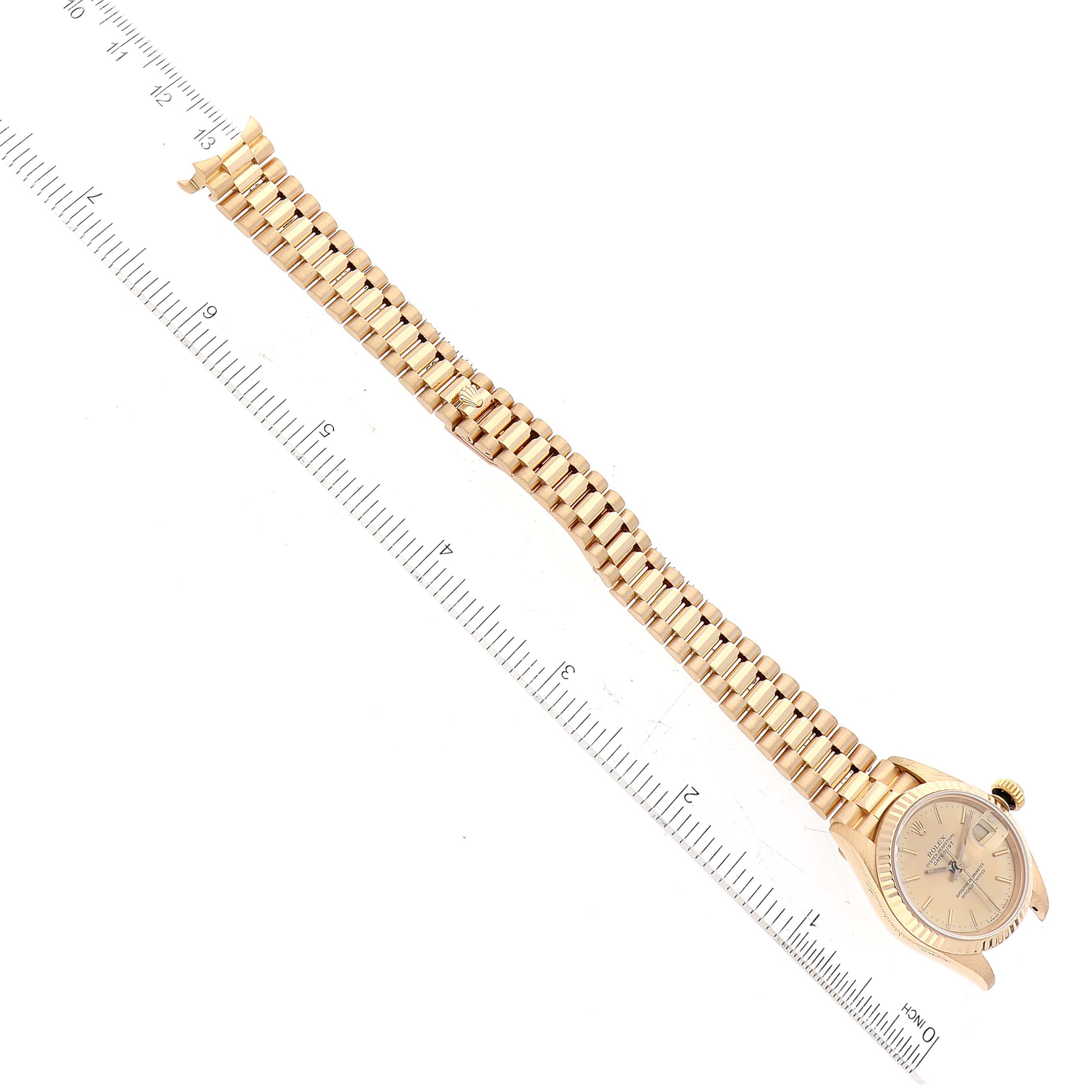 The image shows an overhead view of a Rolex President 69178 Women's Yellow Gold Champagne Dial 69178 Women's Yellow Gold Champagne Dial model watch, displaying its face and full bracelet against a ruler.