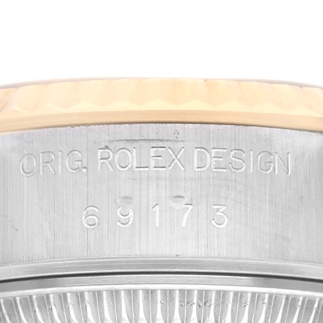 This image shows a close-up of the side of the case of a Rolex Datejust 69173 Women's Steel and Gold (two tone) Champagne Dial 69173 Women's Steel and Gold (two tone) Champagne Dial watch, displaying the model number and "ORIG. ROLEX DESIGN" engraving.