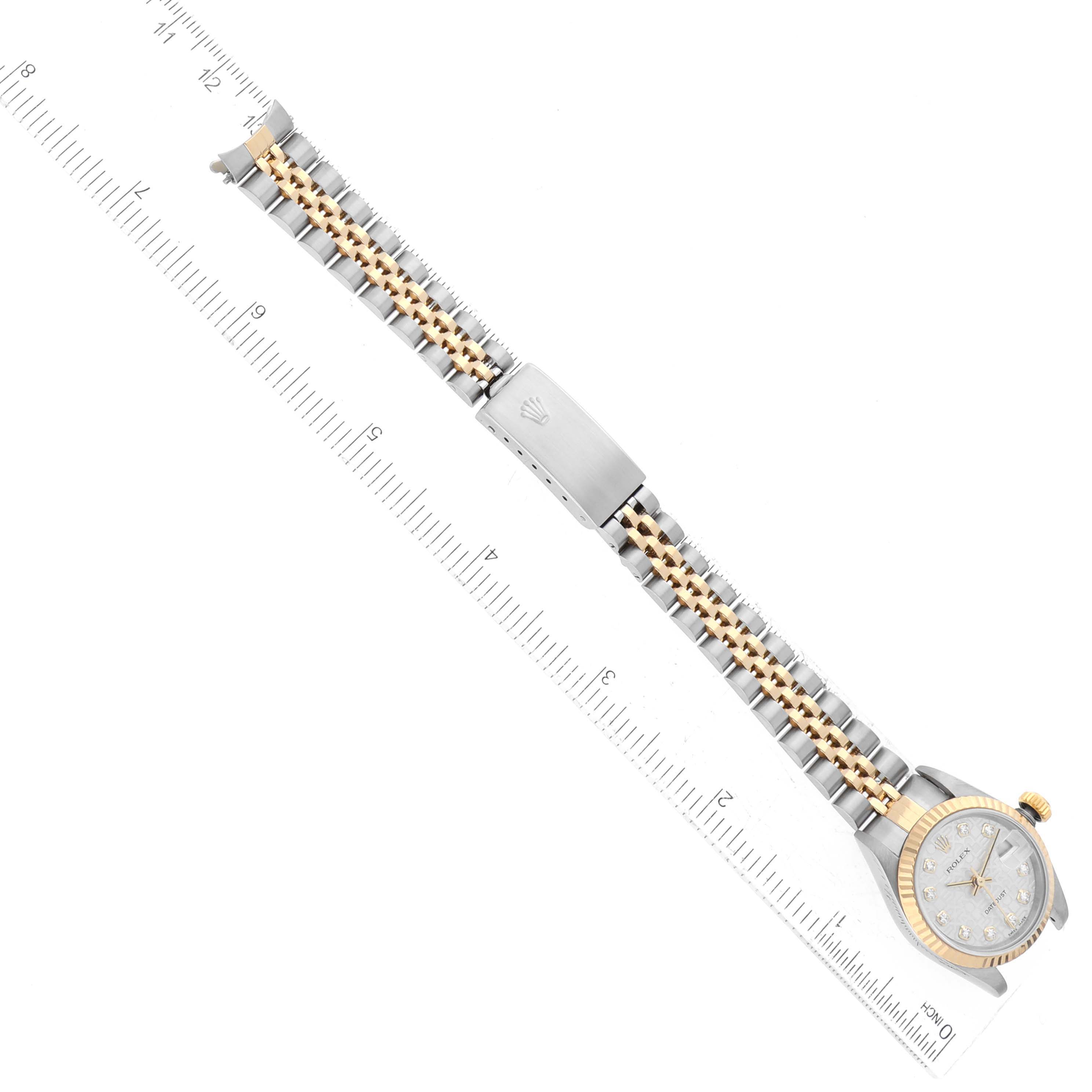 The Rolex Datejust 79173 Women's Steel and Gold (two tone) Silver Dial 79173 Women's Steel and Gold (two tone) Silver Dial watch is shown from a top-down angle, displaying its band, clasp, and face next to a ruler for scale.