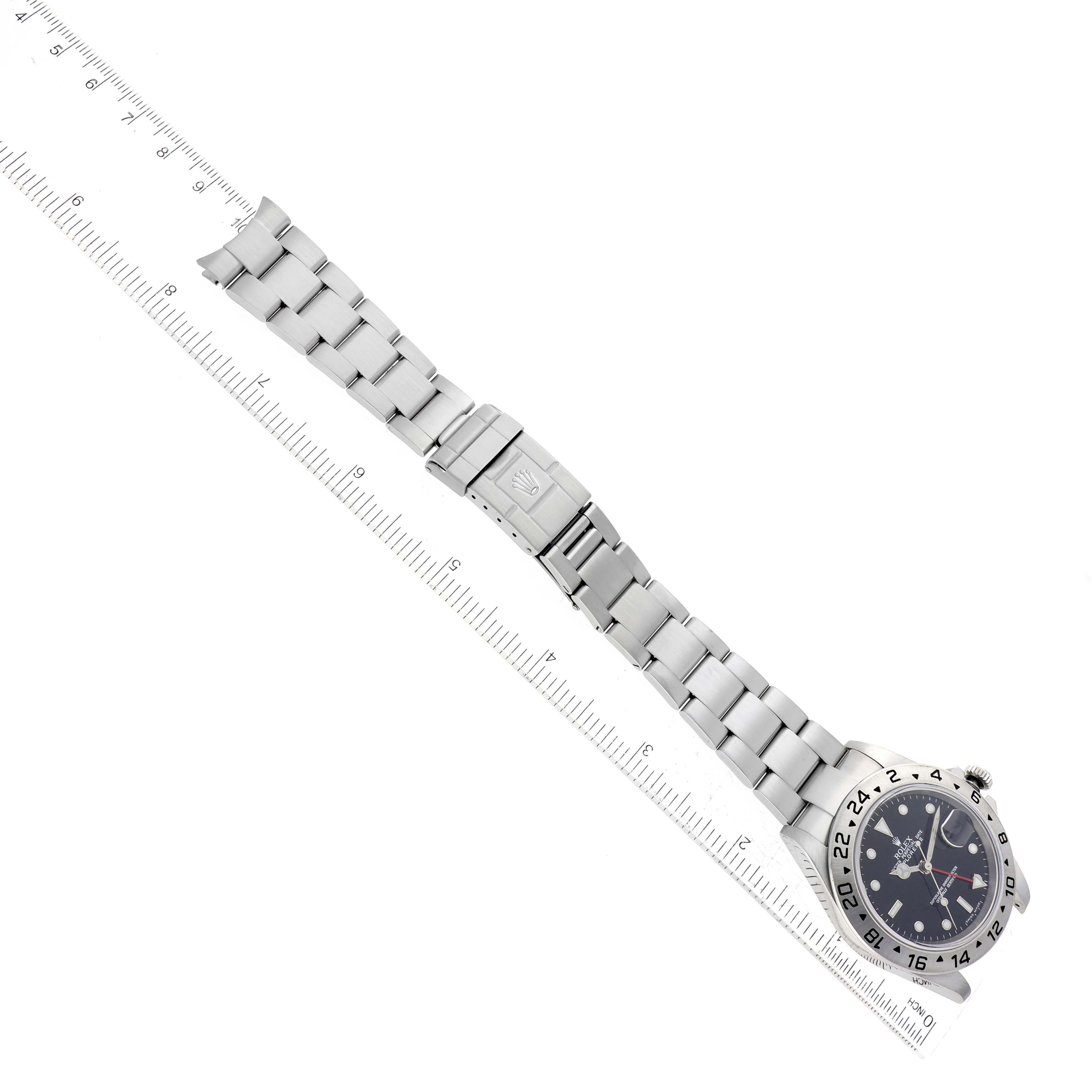 The image shows an overhead view of a Rolex Explorer 16570 Men
s Stainless Steel Black Dial 16570 Men
s Stainless Steel Black Dial watch, focusing on the dial, bracelet, and clasp, with a ruler for scale.