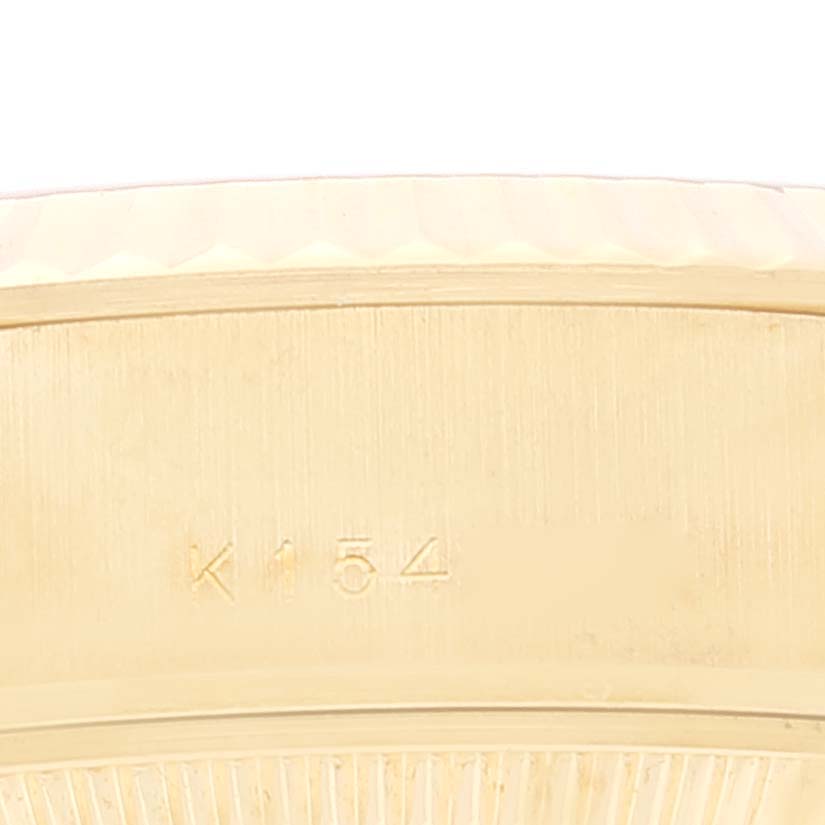This image shows a close-up view of the gold side casing of a Rolex Datejust 79178 Women's Yellow Gold Champagne Dial 79178 Women's Yellow Gold Champagne Dial watch, highlighting the engraved serial number "K154."